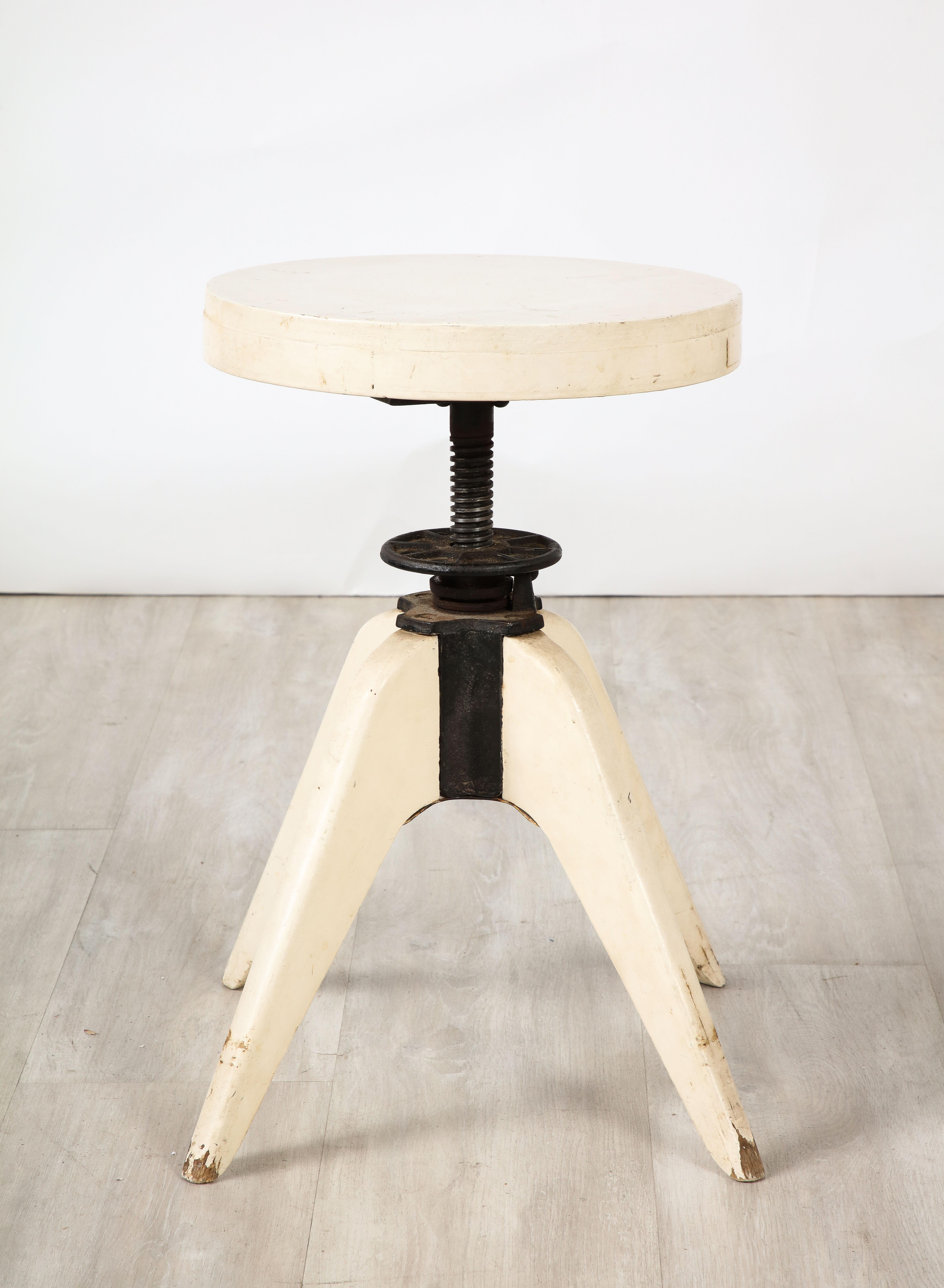 A Jean Prouvé painted four-legged wooden stool with wrought iron adjustable corkscrew mechanism in the center.  Industrial in form and practicality,  while remaining chic in design, highly emblematic of the the works of  Prouvé 
France, circa 1950