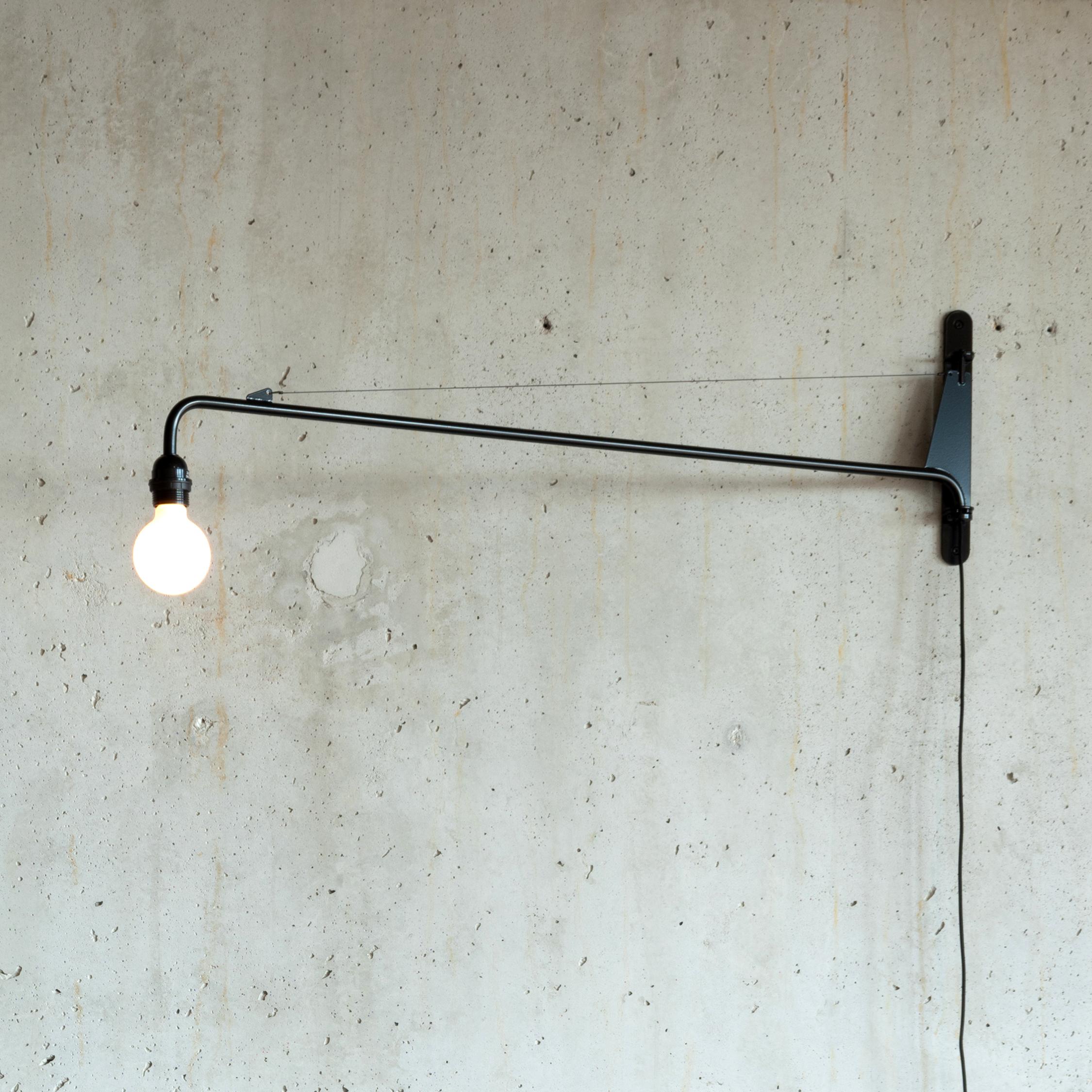 Industrial and minimalistic wall lamp designed by Jean Prouvé and produced by Vitra. Swing (pivoting) arm with black powder coating and light bulb all in excellent original condition with only very light traces of use. The lamp is controlled by a
