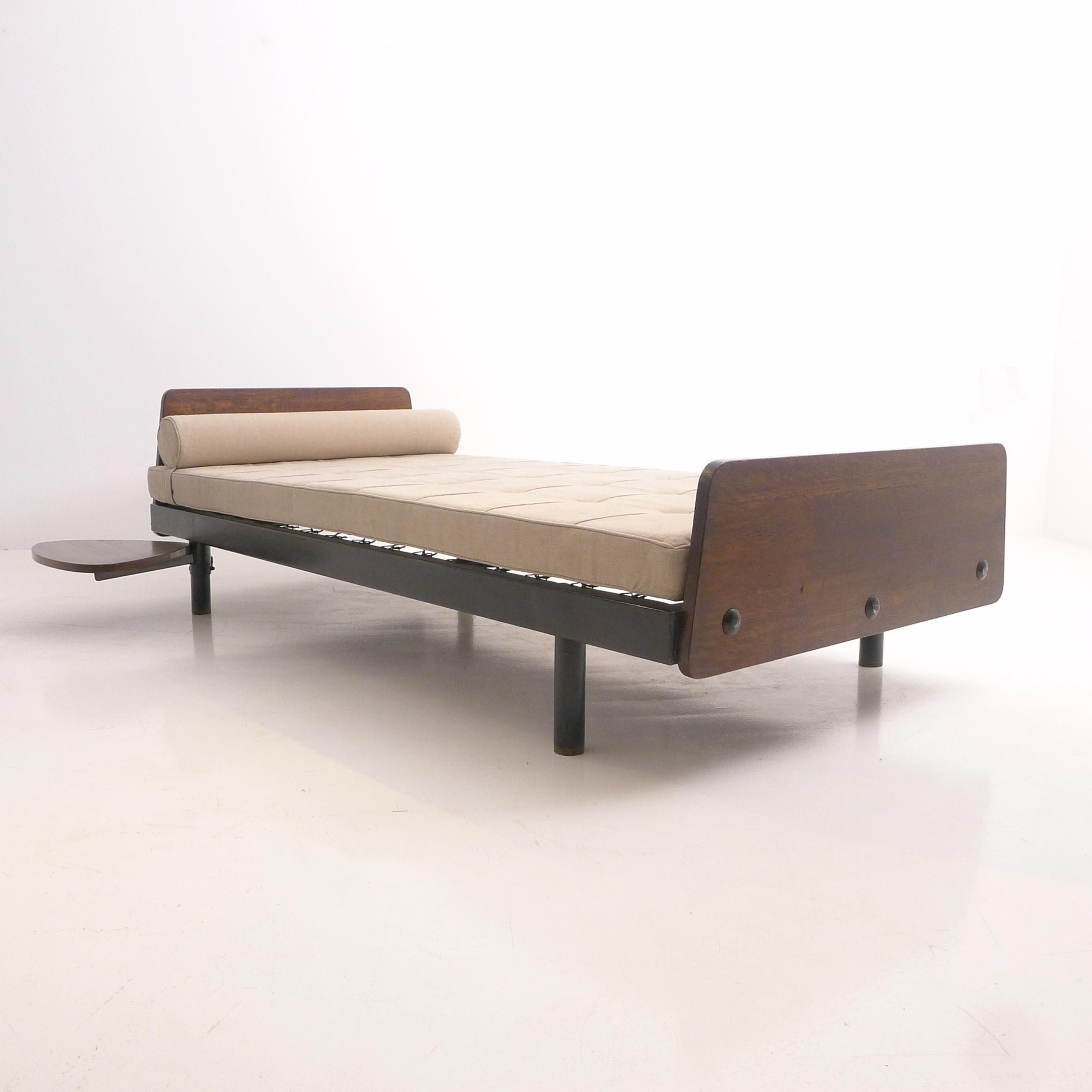 Lit de jour S.C.A.L. original conçu par Jean Prouvé en 1953 et fabriqué par les Ateliers Prouvé en France dans les années 1950.  

Structure en tôle pliée avec pieds tubulaires, têtes et pieds de table en chêne avec rivets et table d'appoint