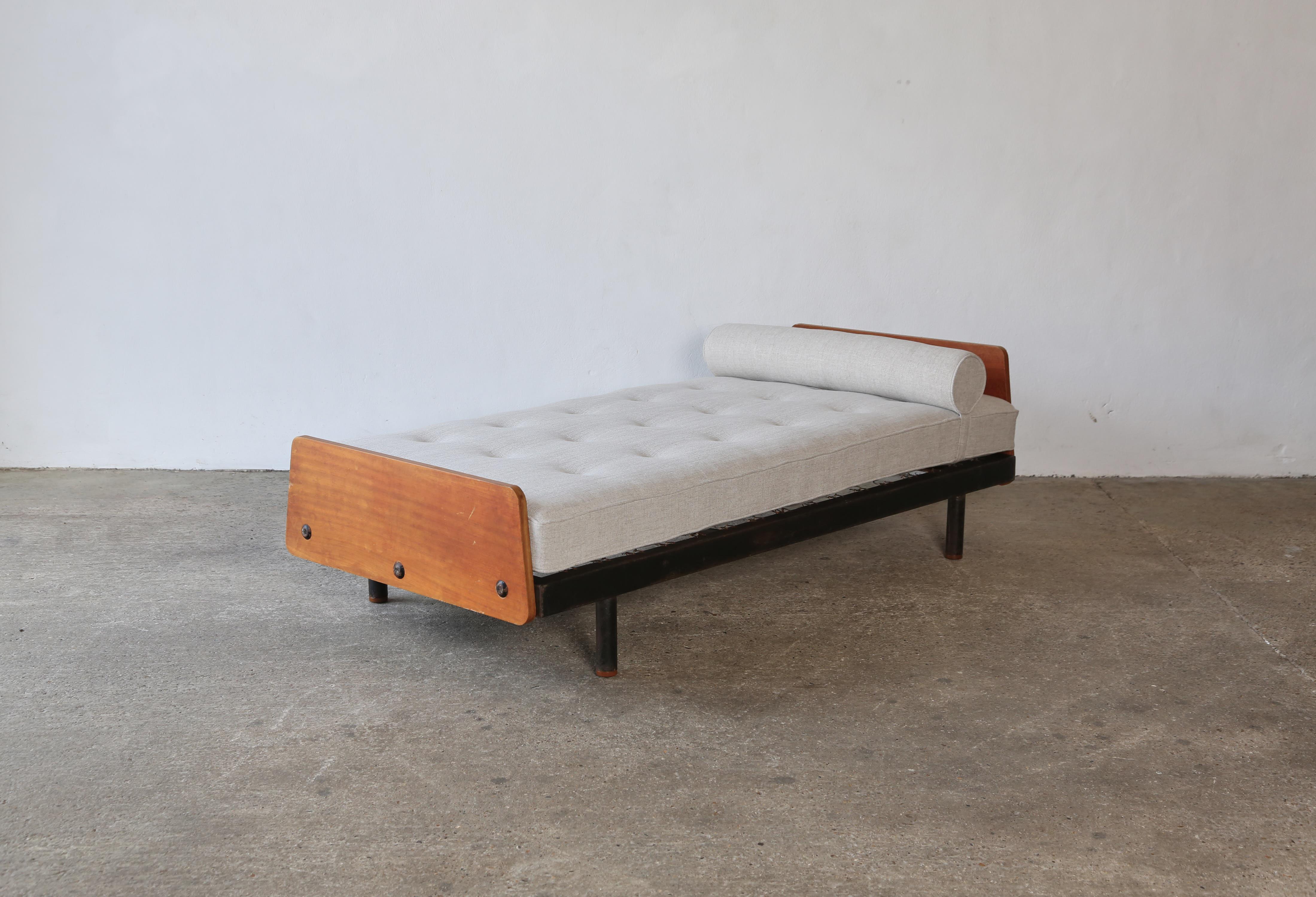 Rare Jean Prouve Daybed from Cité Cansado, Mauritania, 1950s. Mattress and bolster cushion newly upholstered in a neutral washed linen Larsen fabric. The frame and wood are in original condition showing signs of age. New wooden shoes have been