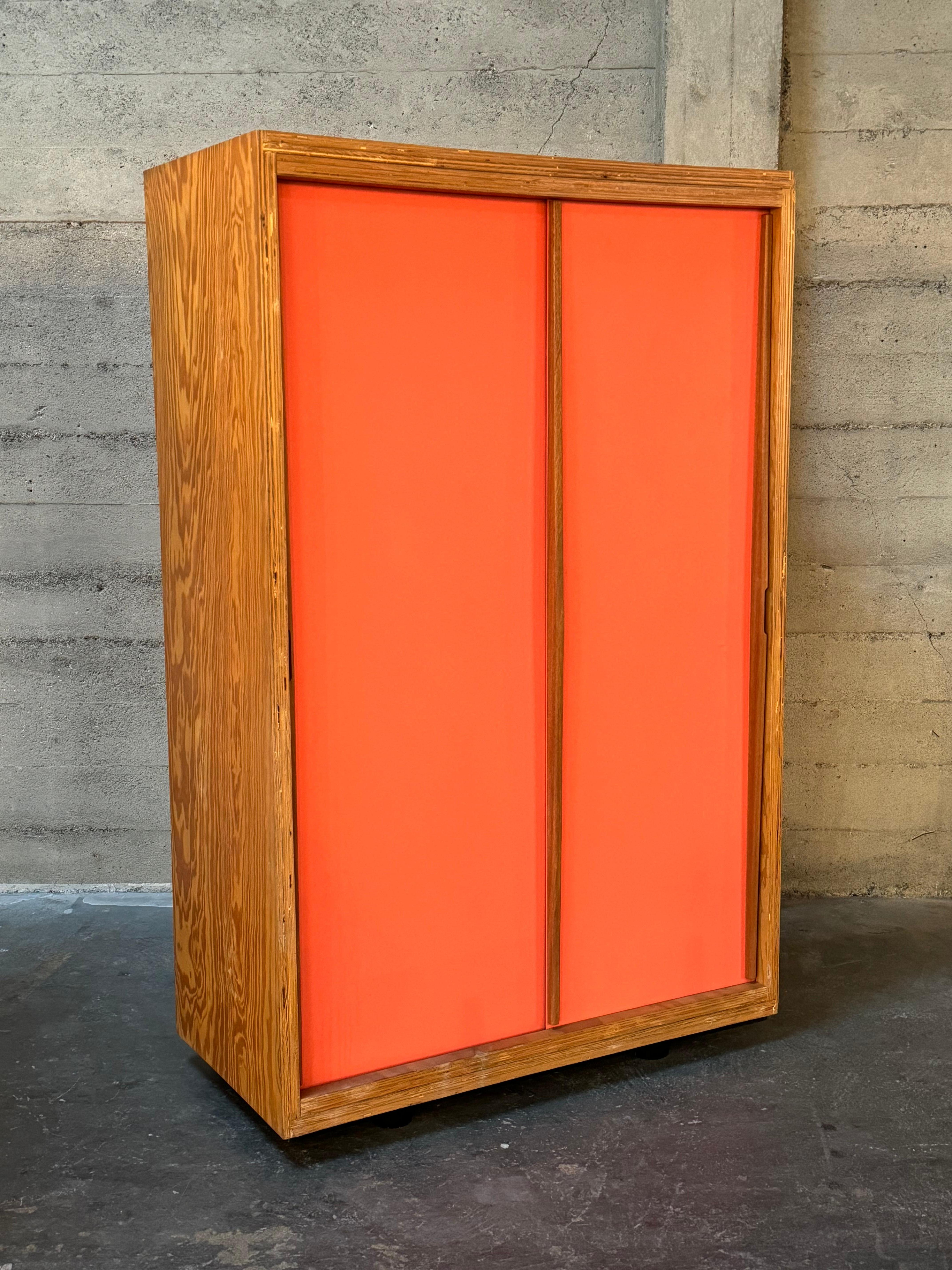 Jean Prouve style cabinets constructed of high grade figurative plywood. With a statuesque present and scale, a true and unique stand out. The two sliding doors are in a salmon pink color with pulls that extend from top to bottom of the cabinet and