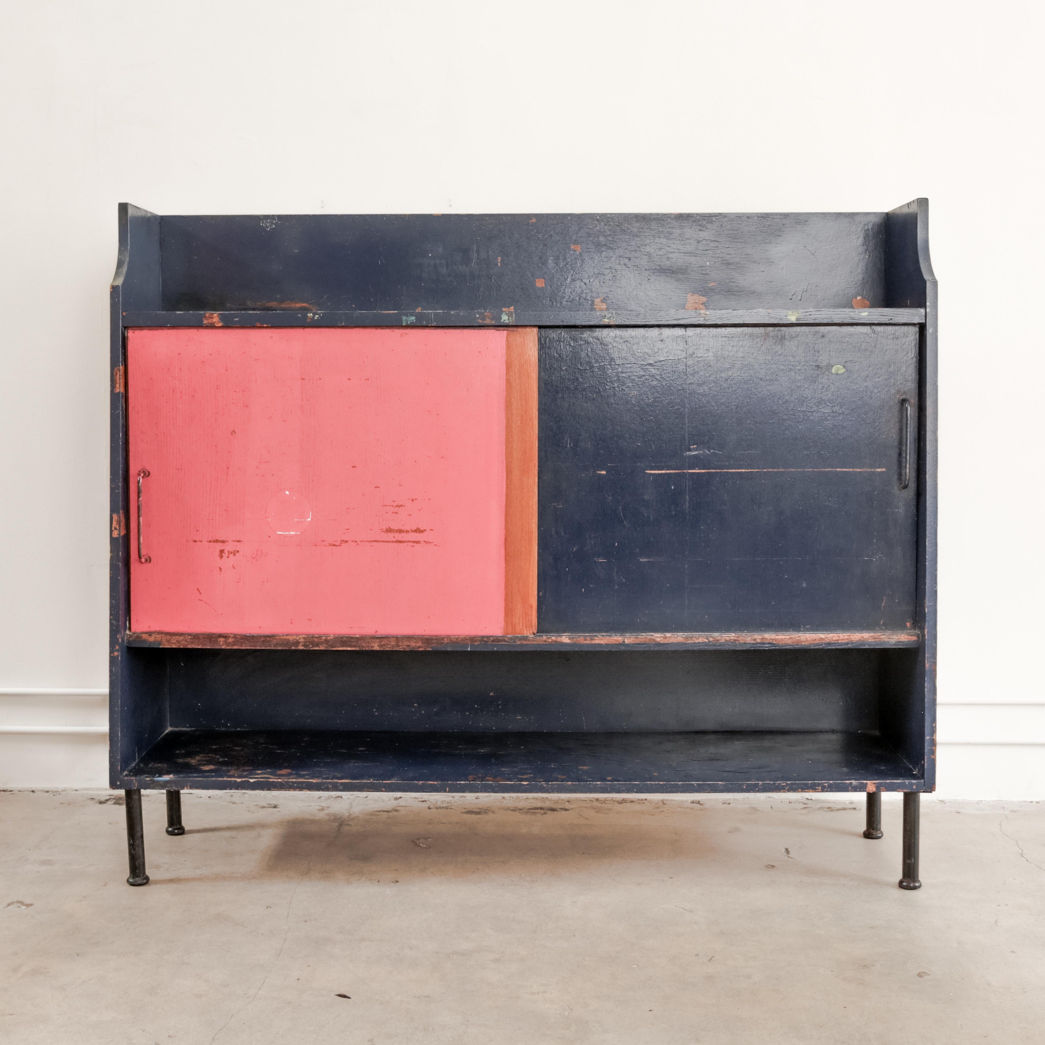 In the style of Jean Prouve a patinated Prussian blue and pink student storage cupboard with sliding bypass doors, from the dormitories of the La Residence Universitaire Jean Zay, France circa 1950's.