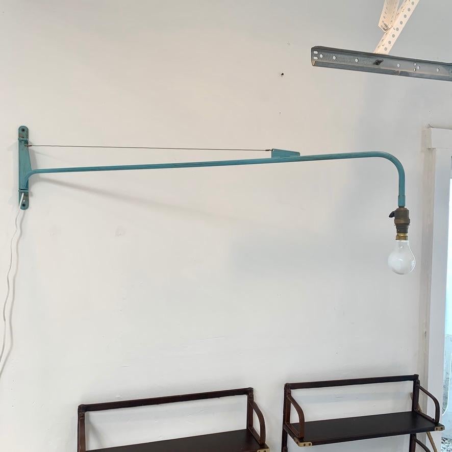 Fantastic vintage articulating wall sconce in the style of Jean Prouve's jib light. Original light blue paint with great patina. Made in the 1950s. European socket and bulb. Wired for the United States. Arm extends 48 inches from the wall and can