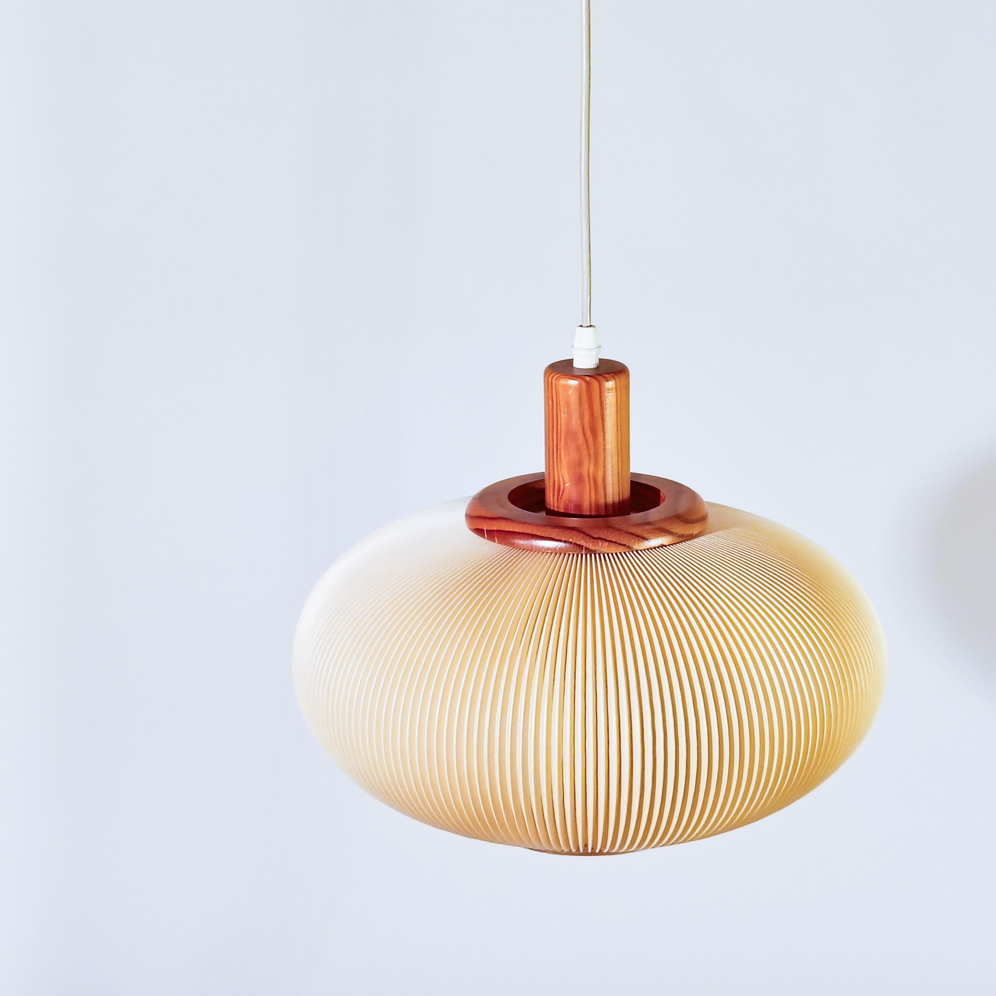 Lámpara de suspensión de mediados de siglo al estilo de las creaciones de Jean Rispal. Estructura de madera de pino natural con barniz satinado y pantalla ovoide beige de acetato de celulosa plisado (acrílico comúnmente llamado 