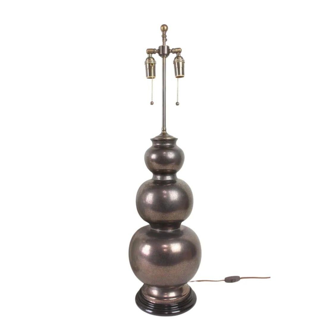 Diese wunderschöne dreifache Keramiklampe von Jean Roger zeigt die unverwechselbare Kunstfertigkeit und raffinierte Eleganz, für die das berühmte französische Töpferhaus bekannt ist. Die Leuchte zeichnet sich durch die anmutig gestapelte Silhouette