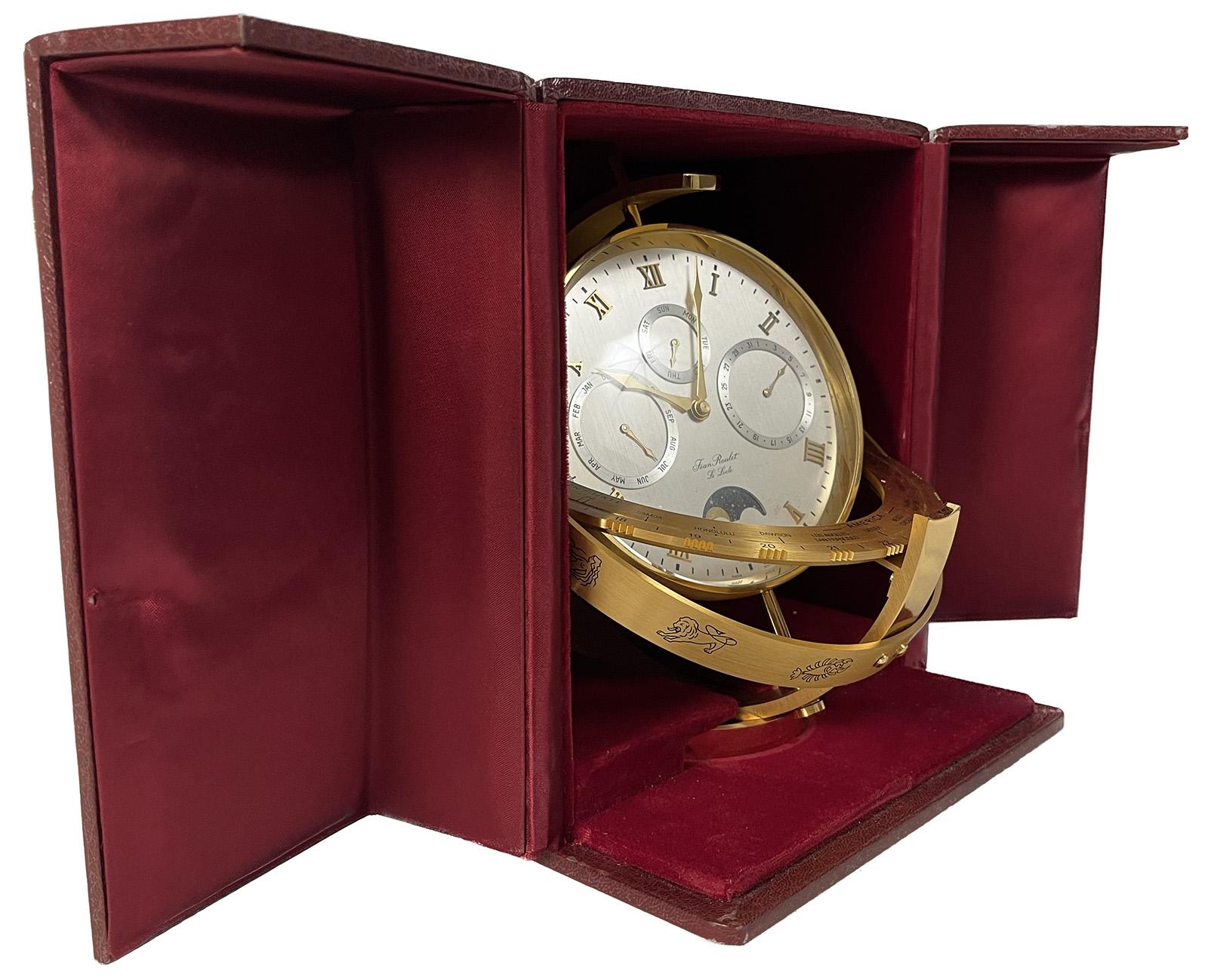 Gold plated quartz Swiss-made Jean Roulet Le Locle with moving moon world time clock, which includes the day/date. Astrology signs also align underneath clock. All fit into a case lined with satin fabric.
