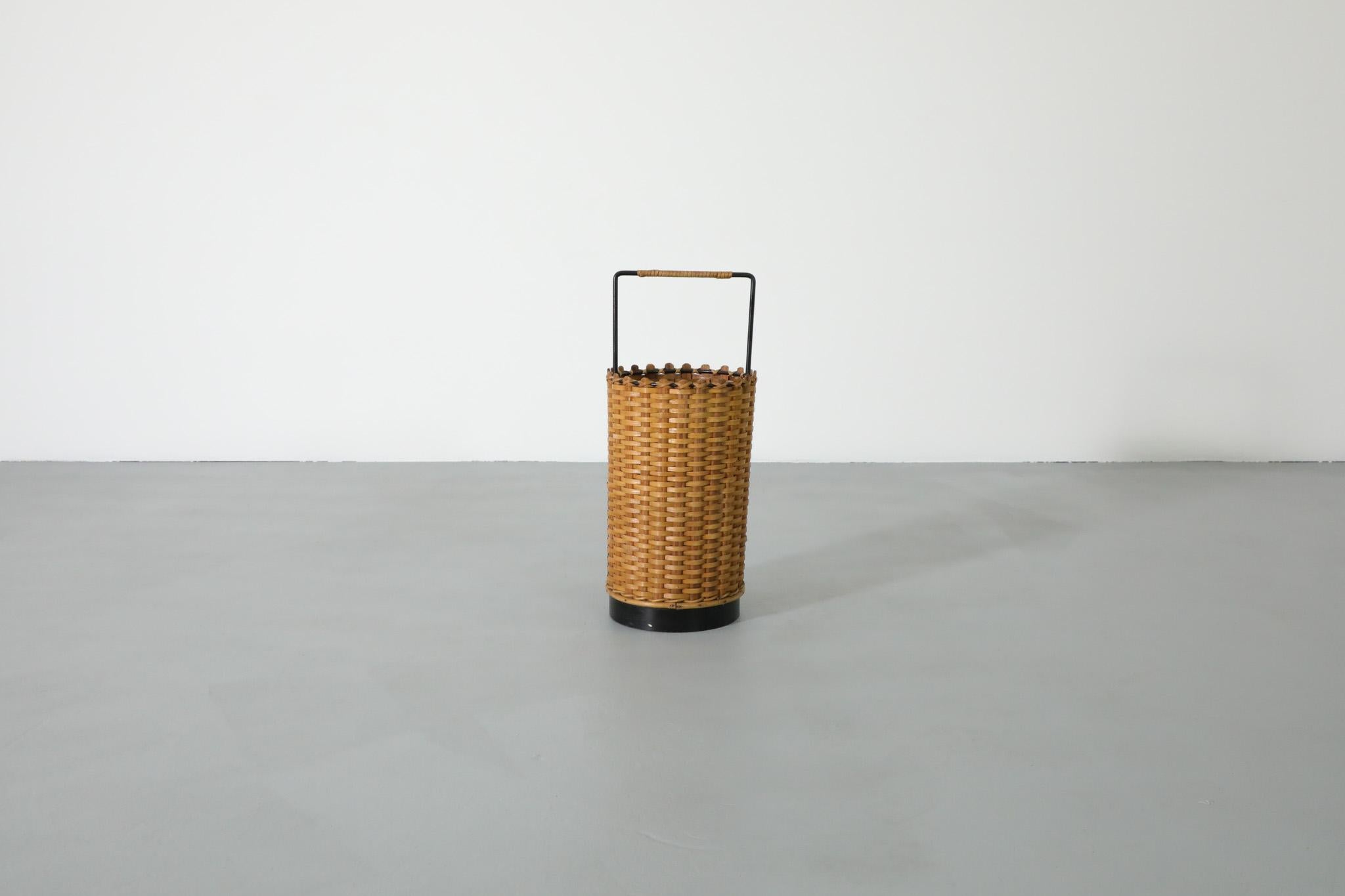 Beautifully woven small, French, Mid-Century rattan basket with black enameled base and rattan wrapped handle.  Perfect as an umbrella stand, waste basket, or small storage bin. In good original condition with some wear consistent with its age and