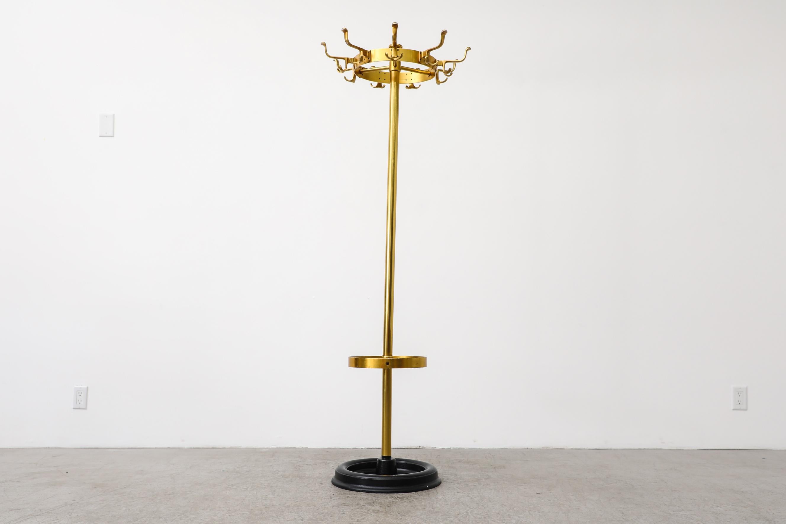 Vintage standing gold enameled metal coat rack. The coat rack has a circular hook crown at the top and an umbrella holder with weighted black painted base. In original condition with visible wear, including scratches, dents and chips. Wear is