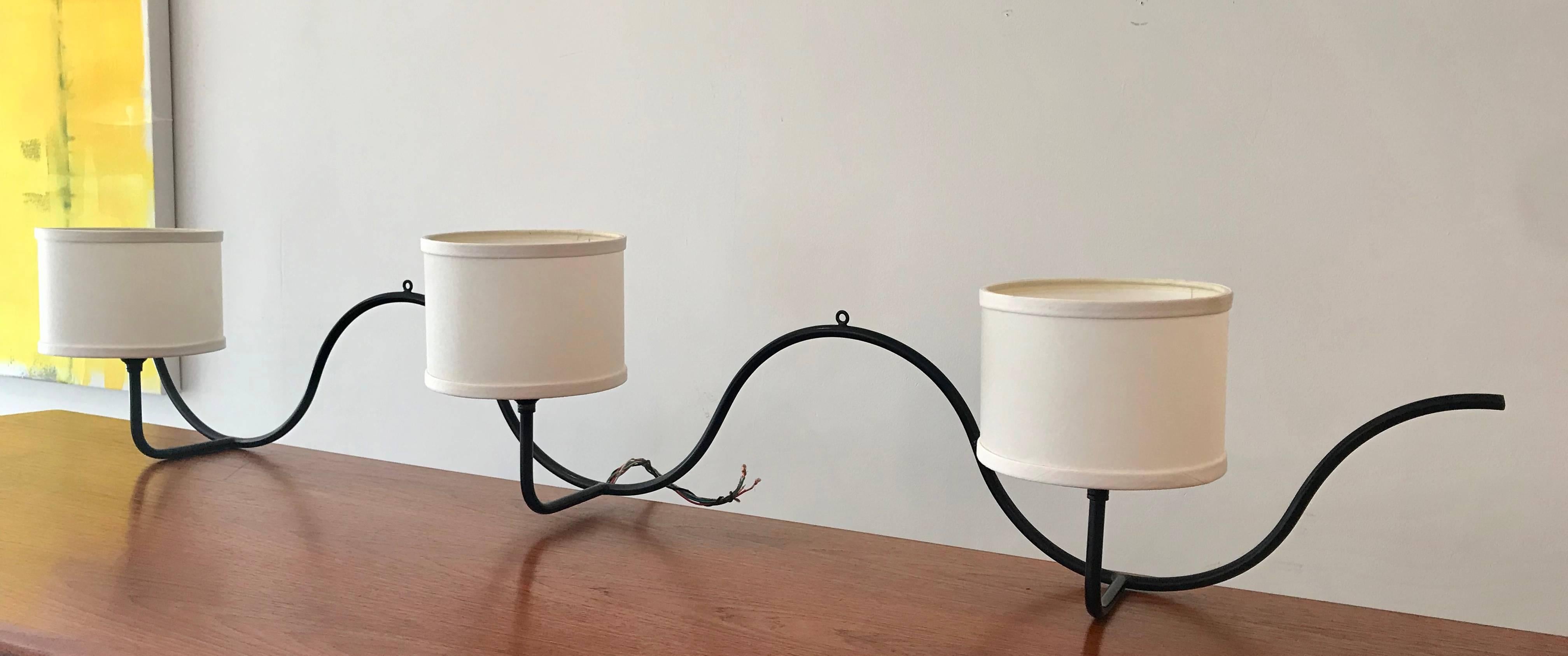 Very rare wrought iron three-light wall lamp by Jean Royere, 1940s. All original with the exception of the shades, that unfortunately are stained, easily replaceable. Rewiring recommended.

A self-taught French craftsman, decorator and furniture