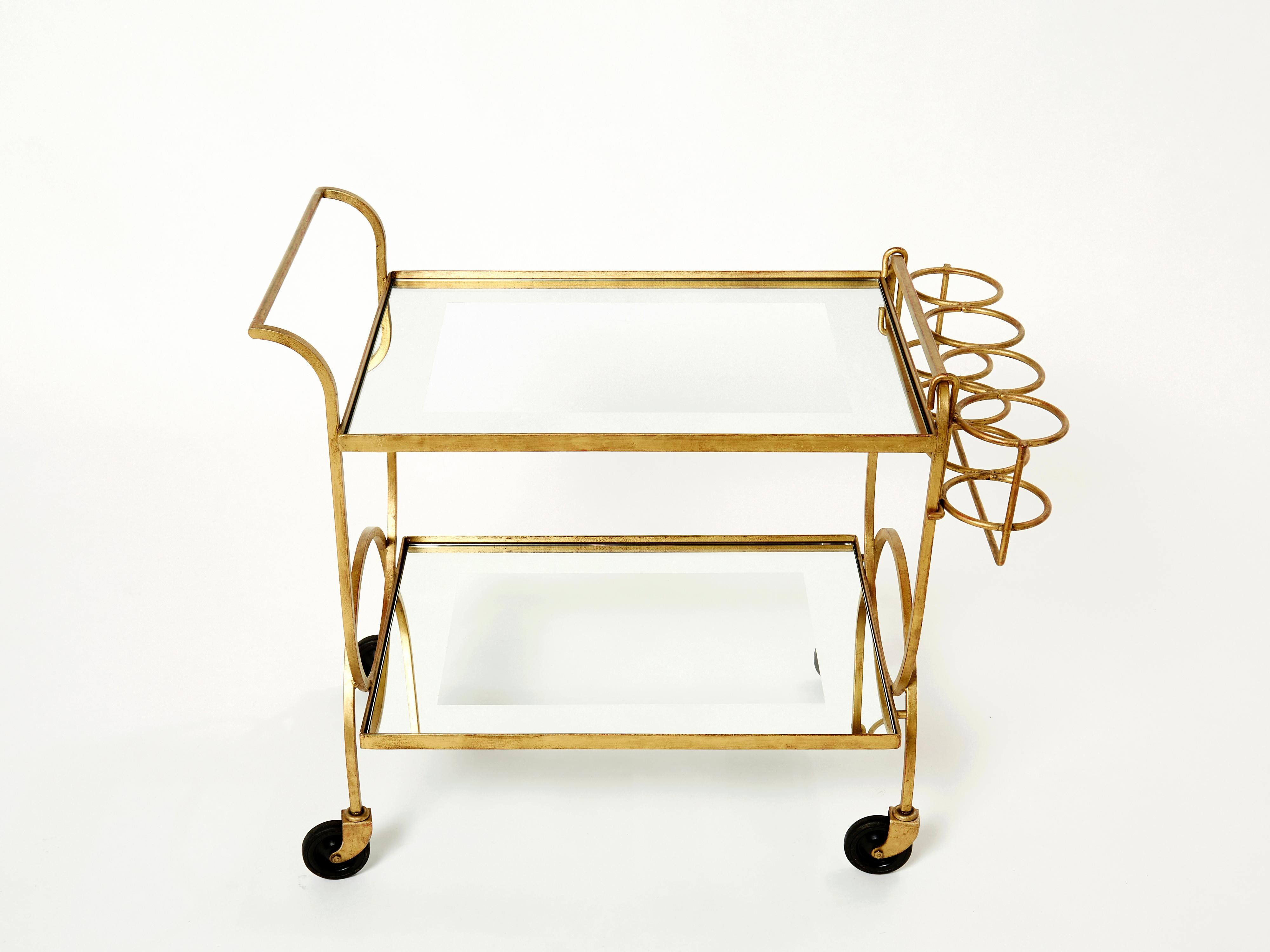 Rare serving trolley by Jean Royère in gilded iron with mirrored glass made circa 1950. Glittering in an antiqued gold gilt finish, this iron craft bar cart adds a glam twist which makes a gracious compliment to both traditional and modern spaces.
