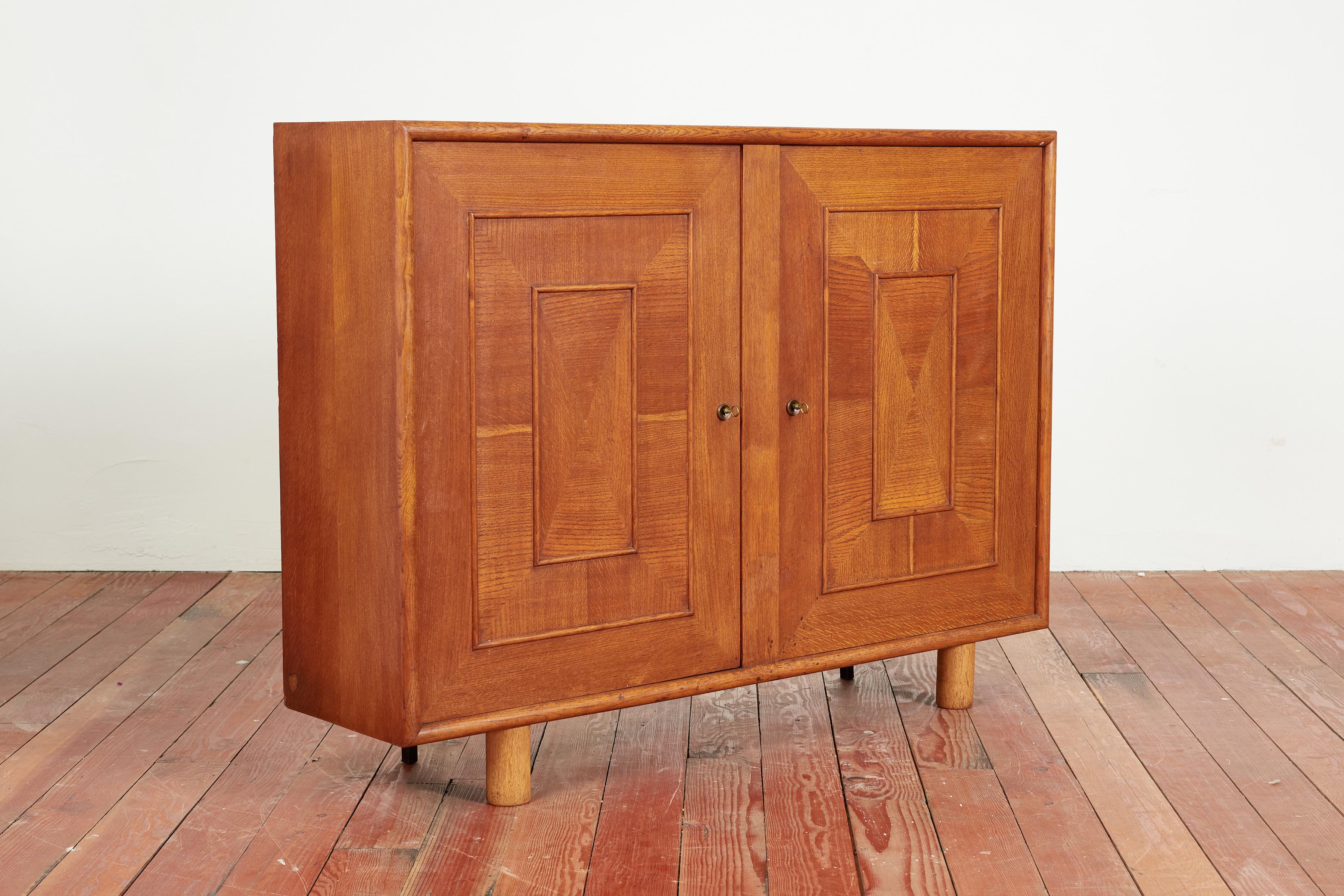 Gorgeous 1940's French cabinet in rich oak
Narrow depth and 2 cabinet doors that open to shelving 
Wonderful pattern on front doors with cylinder front legs 
Rich patina to oak 