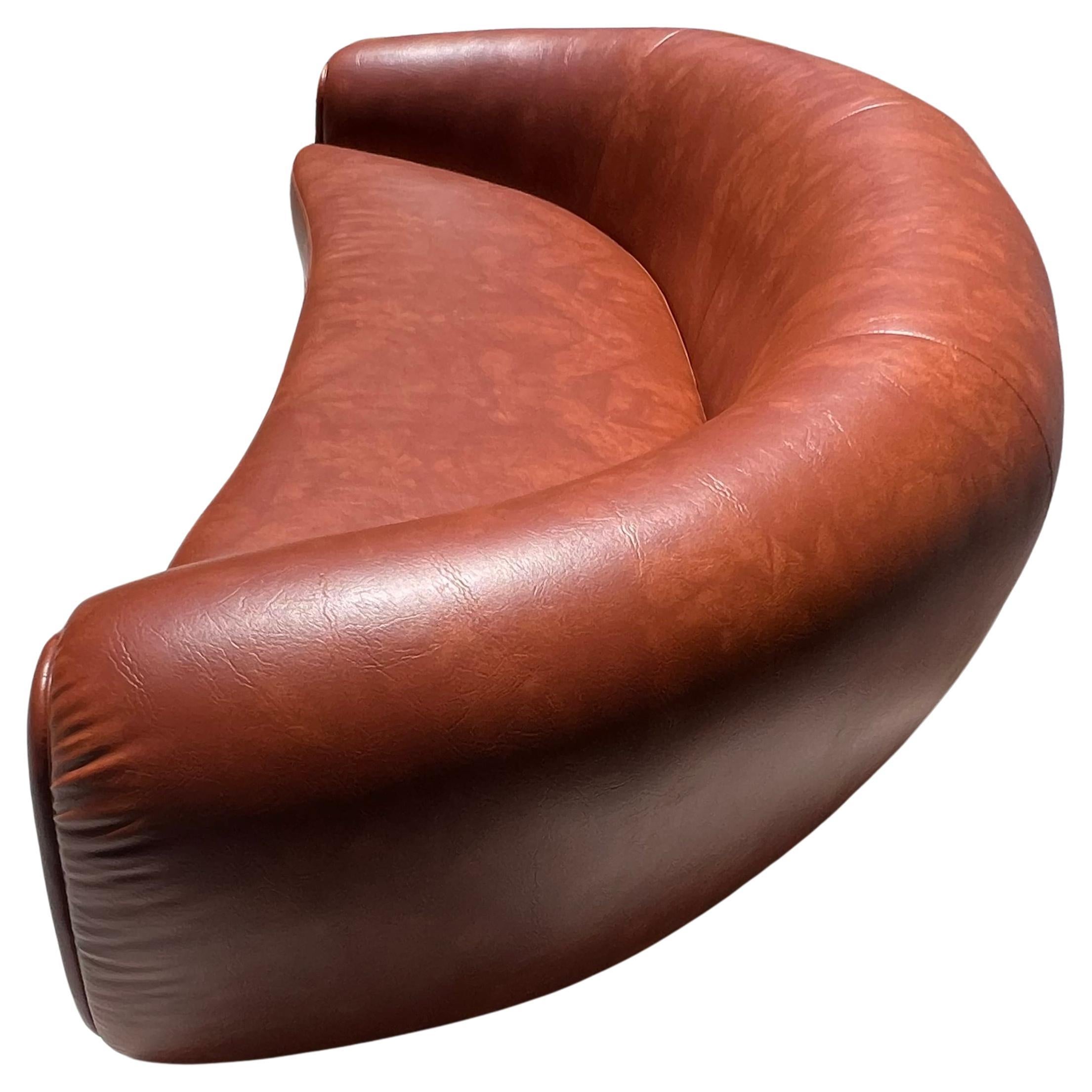A curvy cognac pleather sofa with a bombastically bulging edge and back after Jean Royère, 21st century. Featuring girthy wooden legs and a 70s orange underlay upholstery. Immaculate condition. This was a custom made piece in the style of Jean