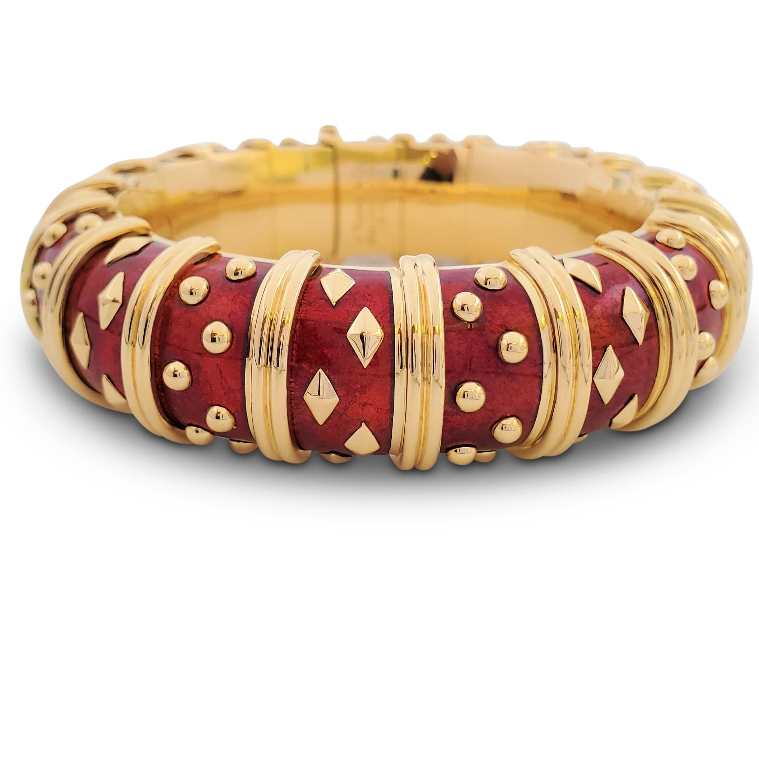An iconic design by Jean Schlumberger for Tiffany & Co. crafted in 18 karat yellow gold with rich red enamel, accented by alternating clusters of raised gold dots and diamond shapes. The semi-flexible bracelet measures 20mm wide. Signed Tiffany &