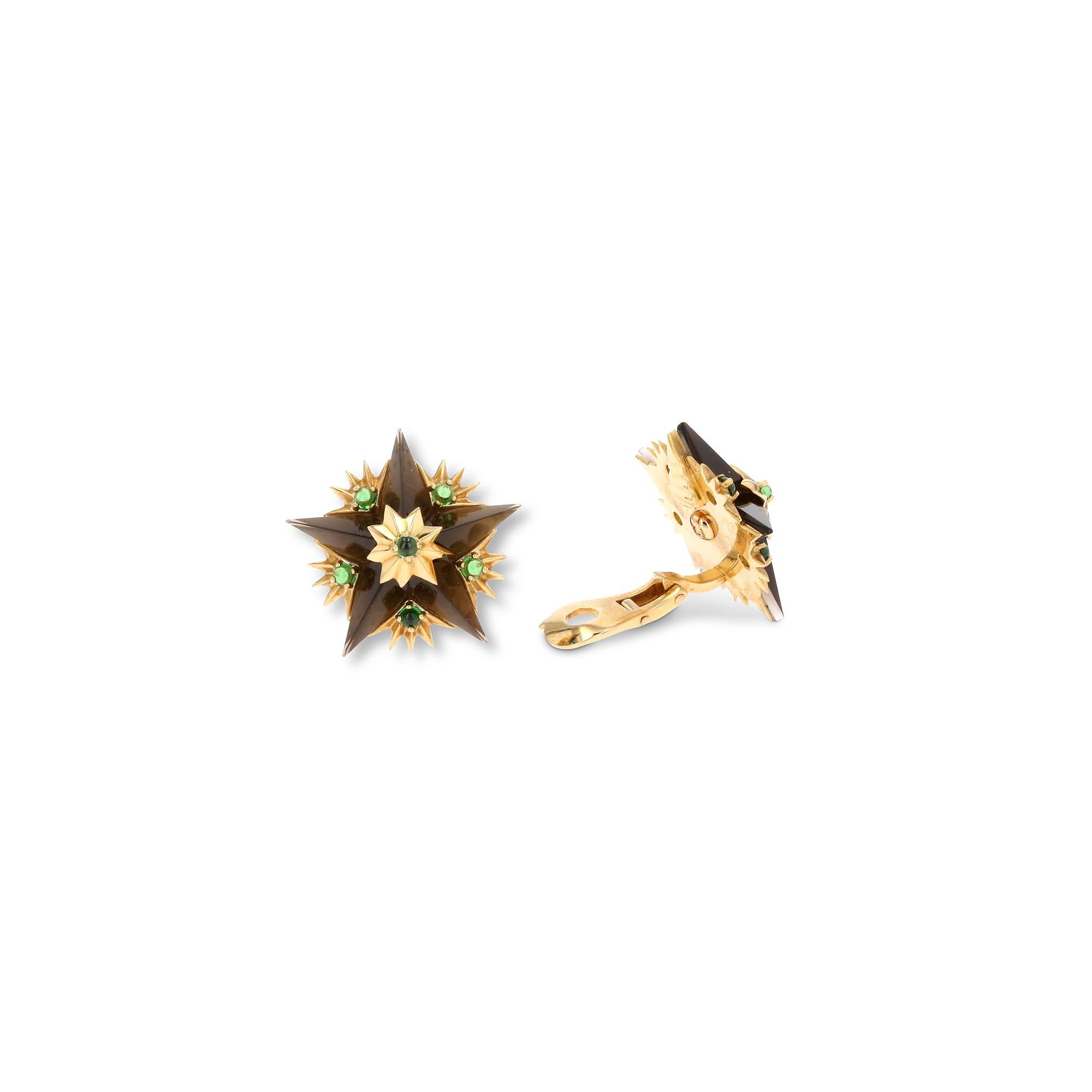 Authentic Jean Schlumberger for Tiffany & Co. ear clips crafted in 18 karat yellow gold. The iconic starburst design features smoky quartz stars accented with tsavorite garnet cabochons. The earrings measure 1 inch at the widest point. Clip backs