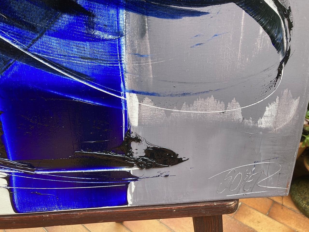 Un sorprendente óleo abstracto sobre lienzo del artista contemporáneo Jean Soyer. Con unas medidas de 80 x 80 cm, esta obra de arte presenta pinceladas atrevidas y amplias en vibrantes tonos azul cobalto, negro intenso y gris plateado sobre un fondo