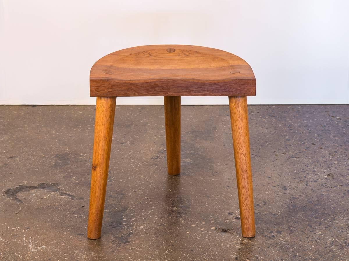 Three-legged 1950s oak stool designed by Jean Touret for Atelier Marolles. Beautifully carved demilune seat is sculpted with care. The attractive aged oak owns it’s original finish, and the three tapered legs have minimal sign of use. Excellent