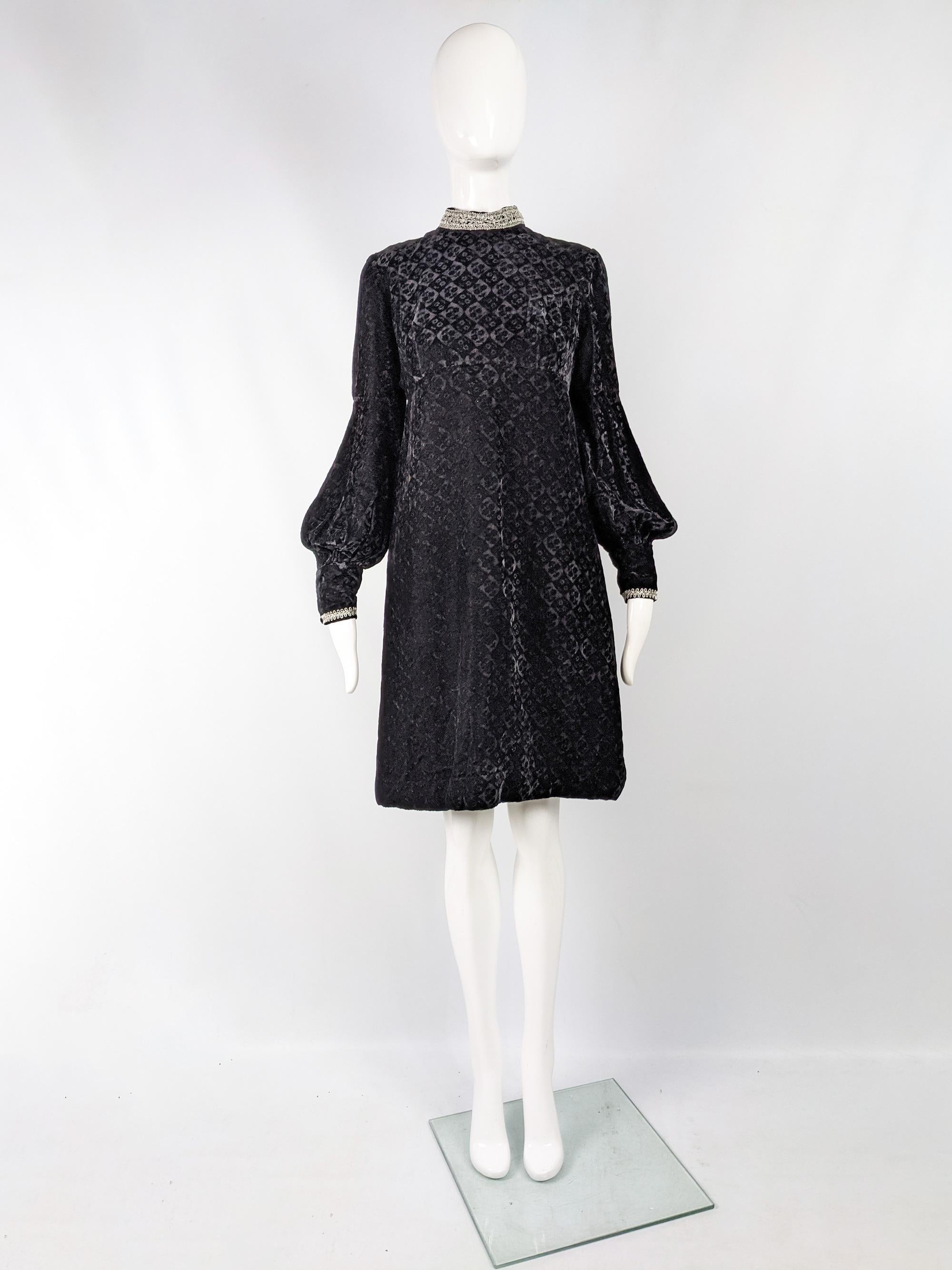 A stunning vintage womens evening / party dress from the 60s by iconic British fashion designer, Jean Varon. In a black floral embossed velvet with balloon shaped lantern sleeves that puff out at the elbow and have a long bishop cuff. It has a high