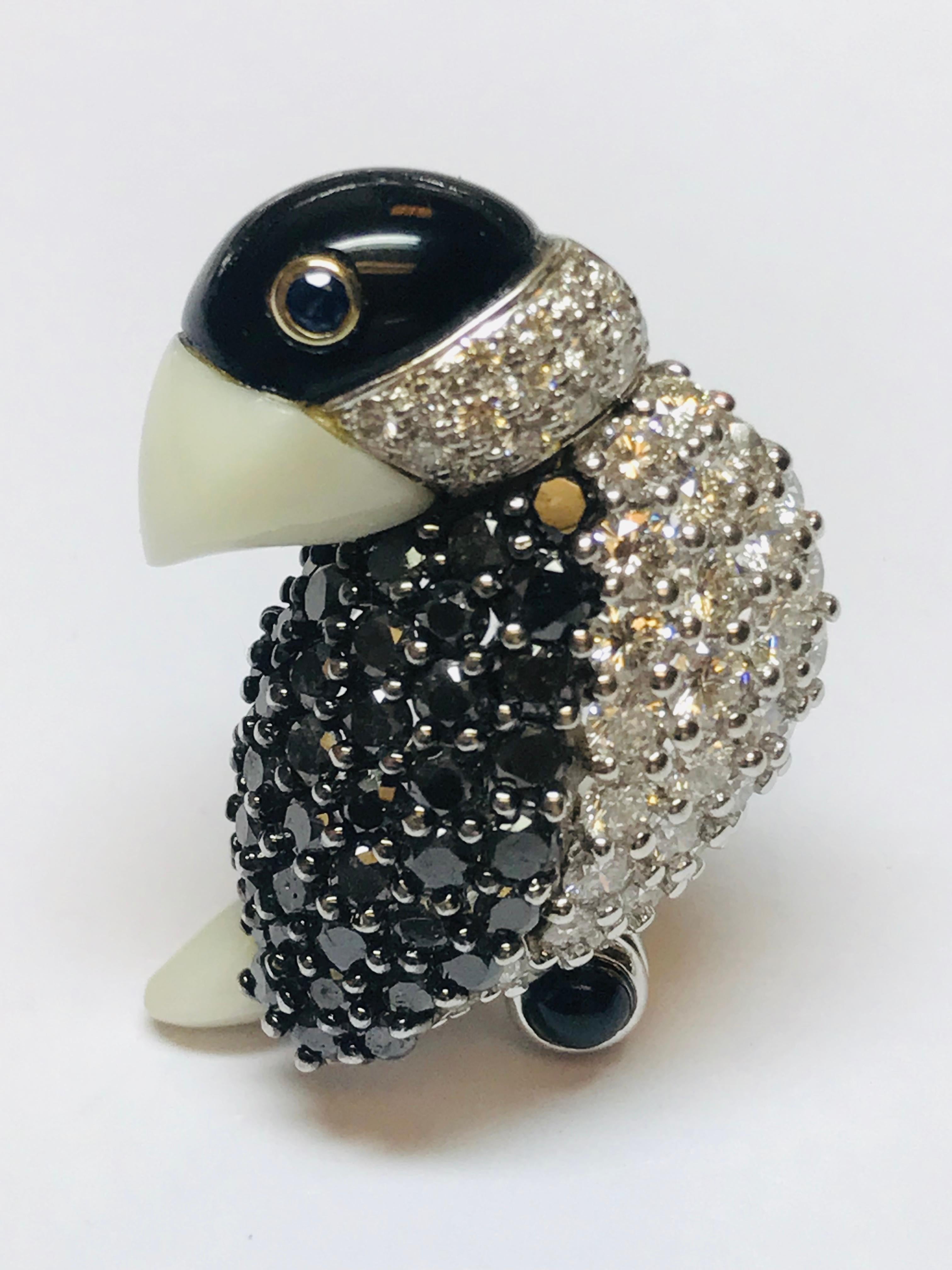 This tropical bird combines 2.23 carats of white diamonds and 2.47 carats of Black diamond, with a white Opal beak and tail, Black Onyx head and Blue Sapphire eye set in 18K white gold! EXQUISITE!!! This piece is also a pendant. 