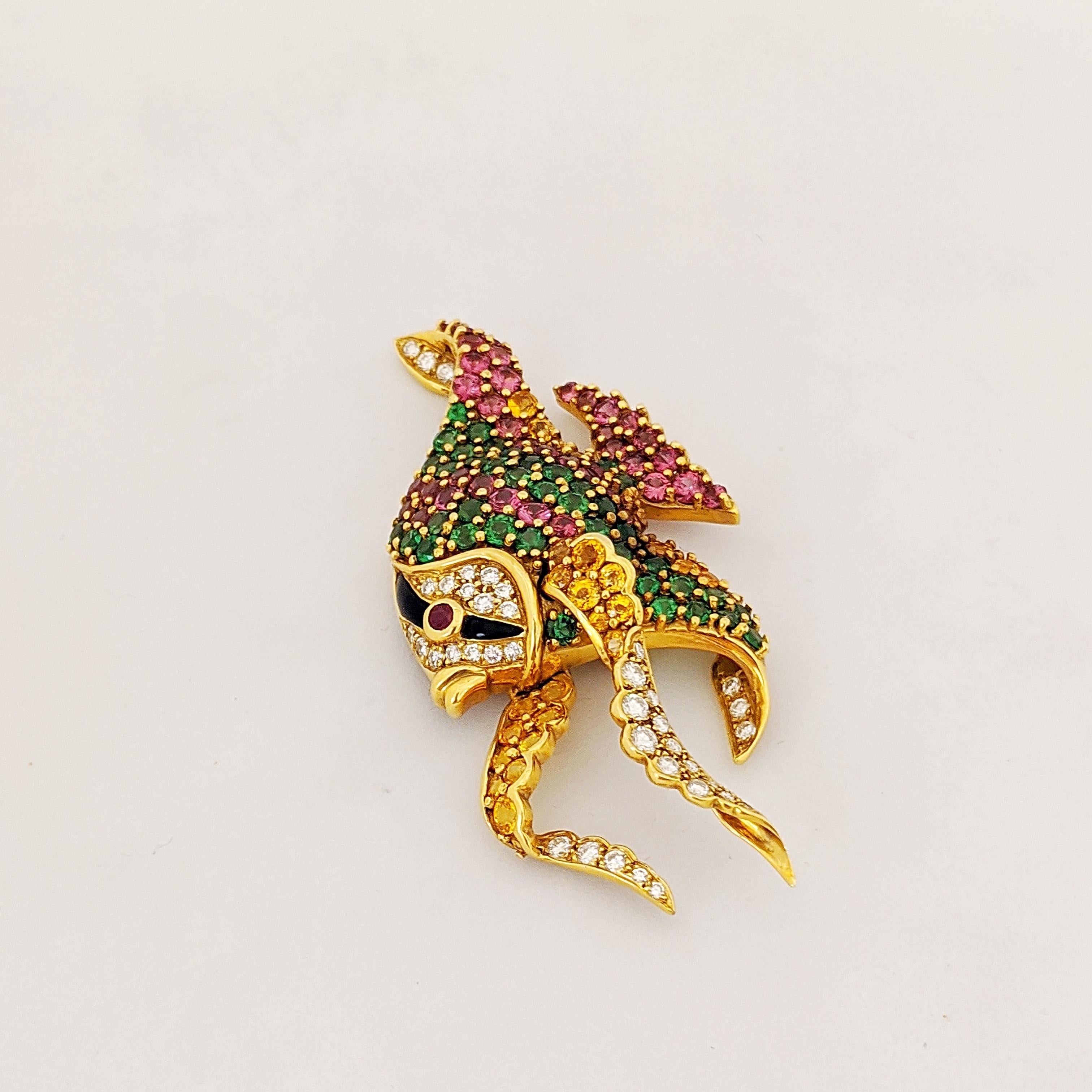 Designed as an angelfish, the body is set with stripes of circular-cut yellow sapphires, pink garnets, and tsavorites. The head with pavé-set diamonds, black onyx stripe and circular-cut ruby eye. The fins are bezel set circular-cut diamonds and