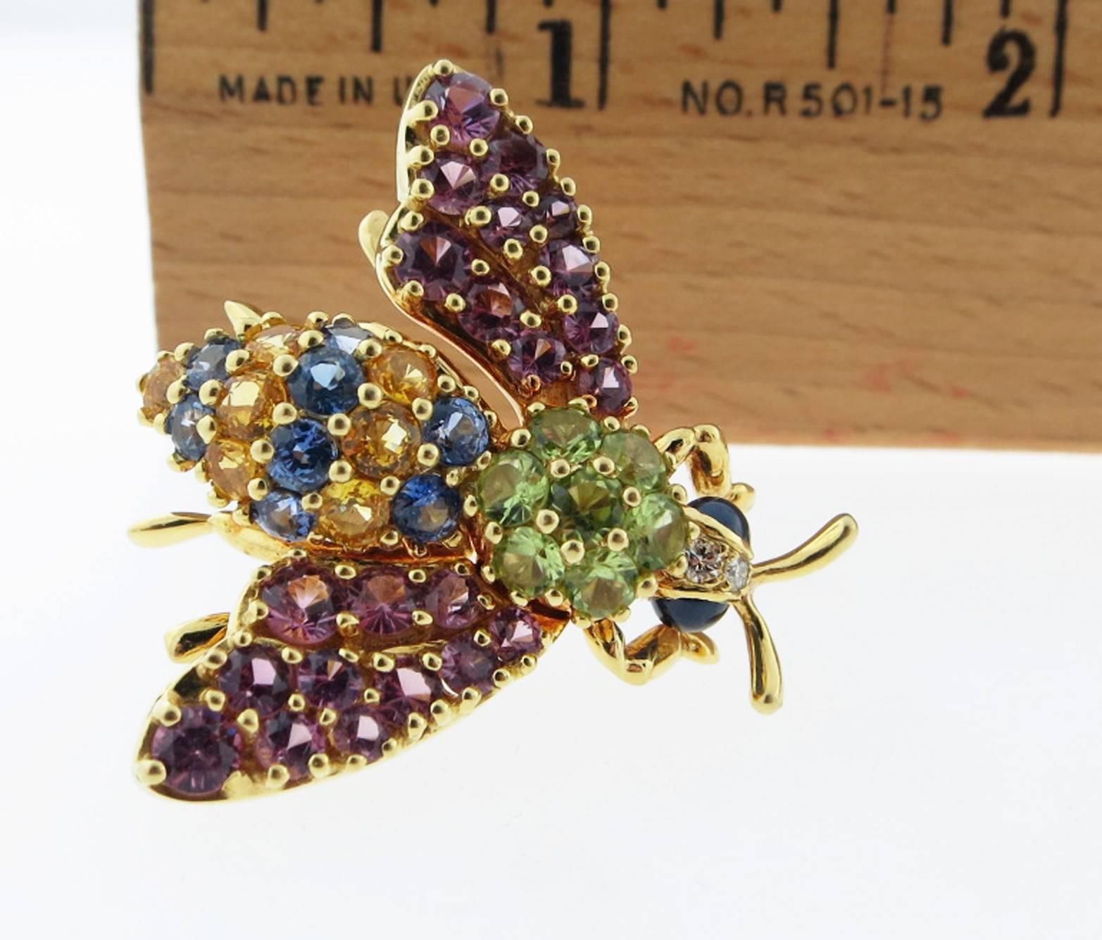 Vibrant  18kt. yellow gold fly brooch set with a mix of faceted natural sapphires, peridot, and diamonds. The brooch measures approx 1  1/2 inches in length. Signed Jean Vitau.