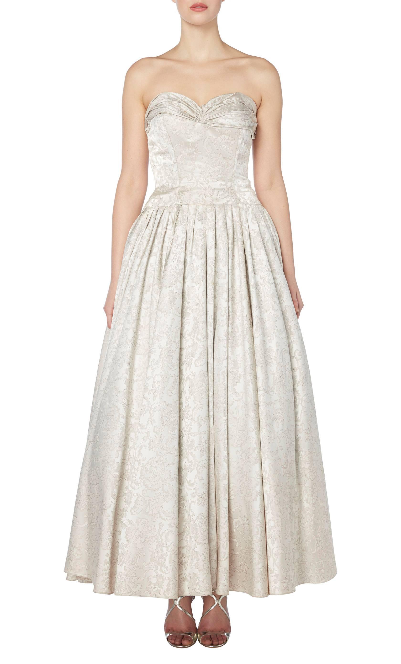 This stunning strapless gown is a rare example of haute couture by Lanvin herself. Perfect for a formal event or a wedding dress, the gown is constructed in pure silk with an abstract floral motif and features a gathered neckline and internal
