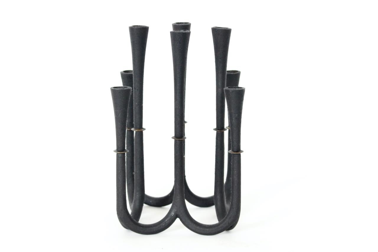 Jens Harald Quistgaard Cast Iron & Brass 8 Arm Candle Holder, Circa 1960. Featuring a balanced, curved enameled black cast iron open candlestick form base, with varied height candle sticks detailed with brass ring detail to each. Utilizes thin