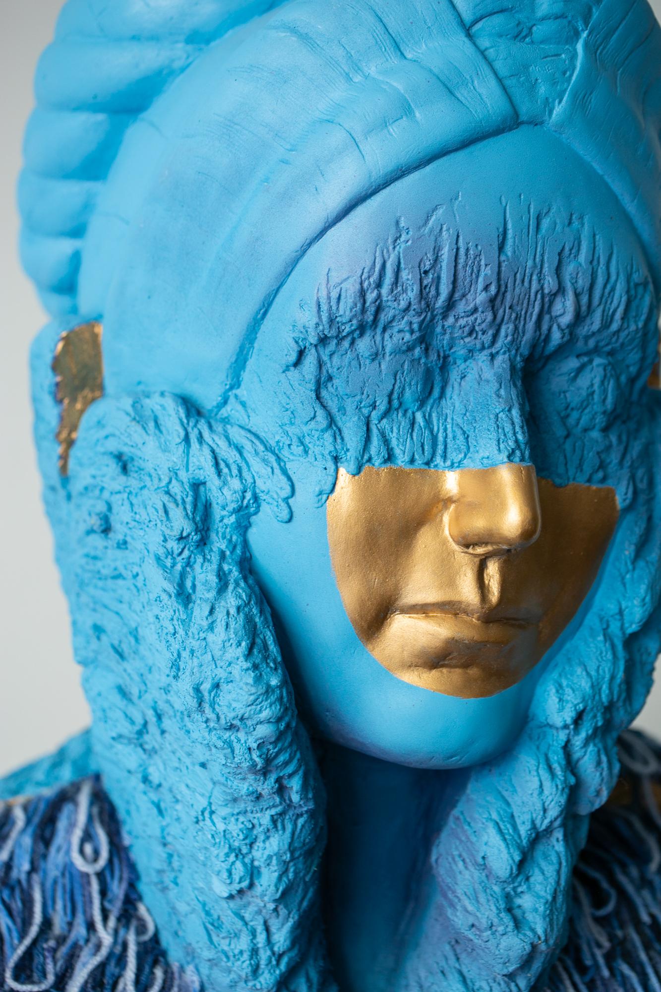 This blue and gold-colored figurative sculpture titled 