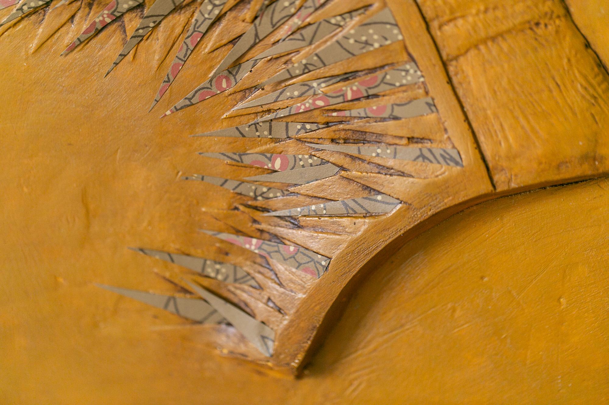Esta escultura figurativa naranja para colgar en la pared titulada 