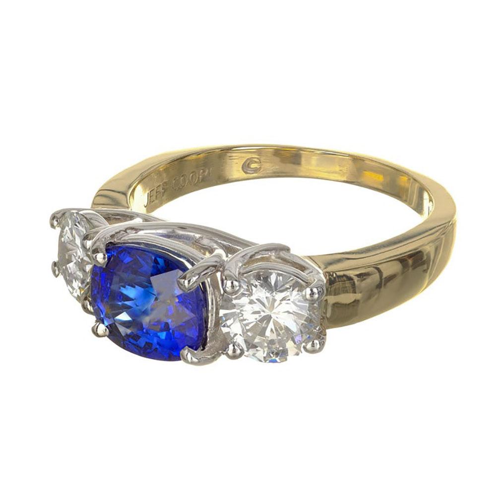 Jeff Cooper sapphire and diamond three-stone engagement ring. Set with two bright sparkly brilliant cut diamonds on each side of a GIA Certified Oval sapphire set in 18k yellow gold and platinum. 

1 cushion cut oval blue sapphire Approx. Total