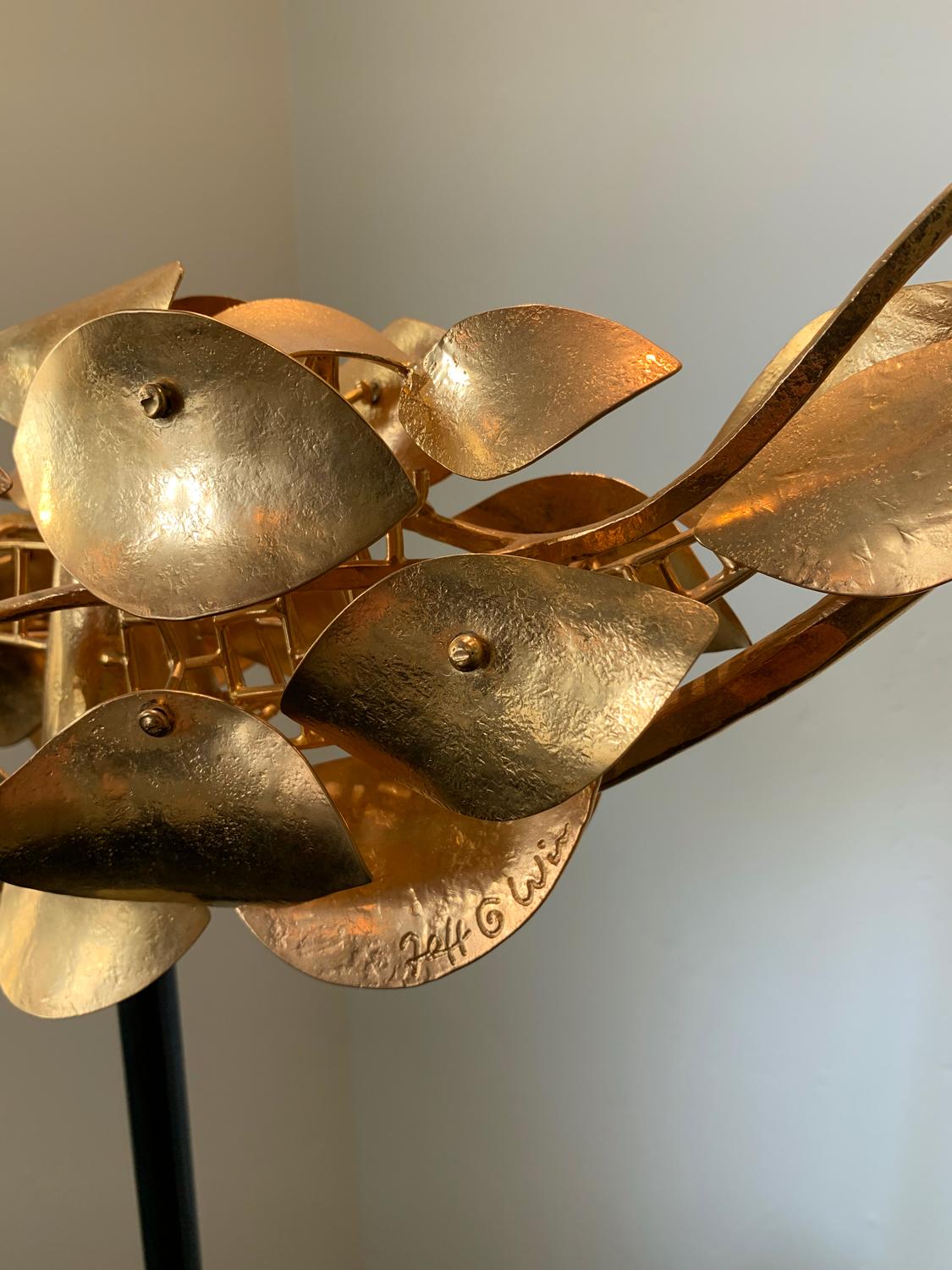 Un fantastico pesce realizzato con scaglie di bronzo formate a mano e placcate in oro 24 carati! Le scaglie si librano su una base di cemento scuro e lucido, ondeggiando delicatamente e scintillando alla più leggera brezza. La scultura è esposta qui