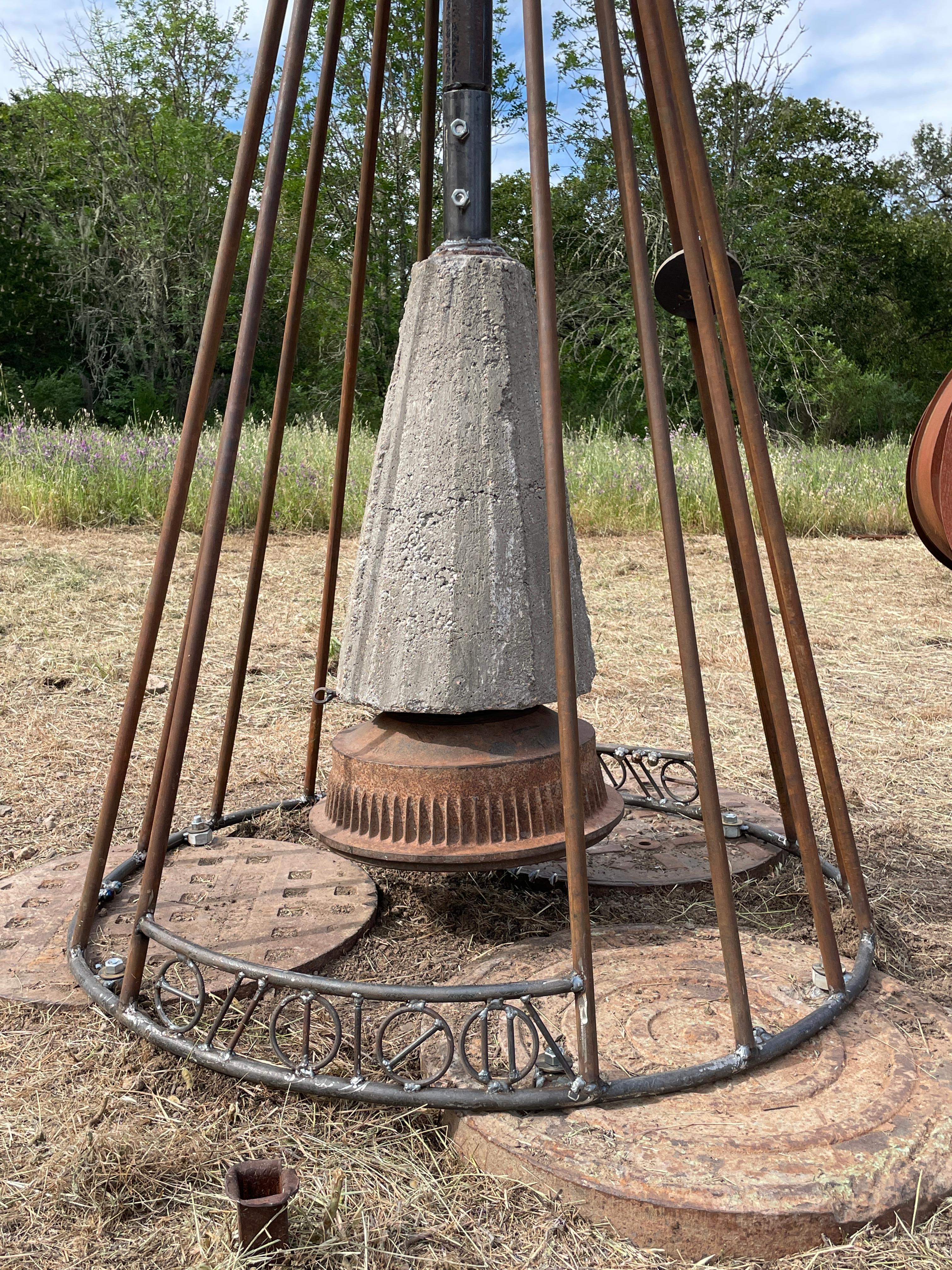 Cette étonnante sculpture cinétique est faite d'acier soudé, revêtu de poudre et peint en blanc et dans des tons dégradés de rose métallique, en spirale au sommet d'un grand poteau. La section supérieure colorée est contrebalancée par un tambour de