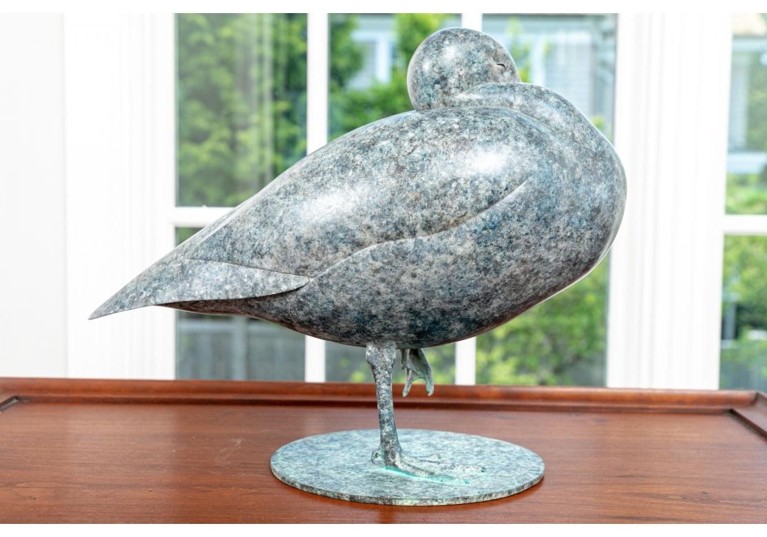 Bronze sculpture of a lesser snow goose with pierced eyes, precariously balanced on one leg and surmounted on a circular base. The goose in a multi-tonal blue/green patina.
Signed on the base and numbered 2/12 along with the foundry mark as