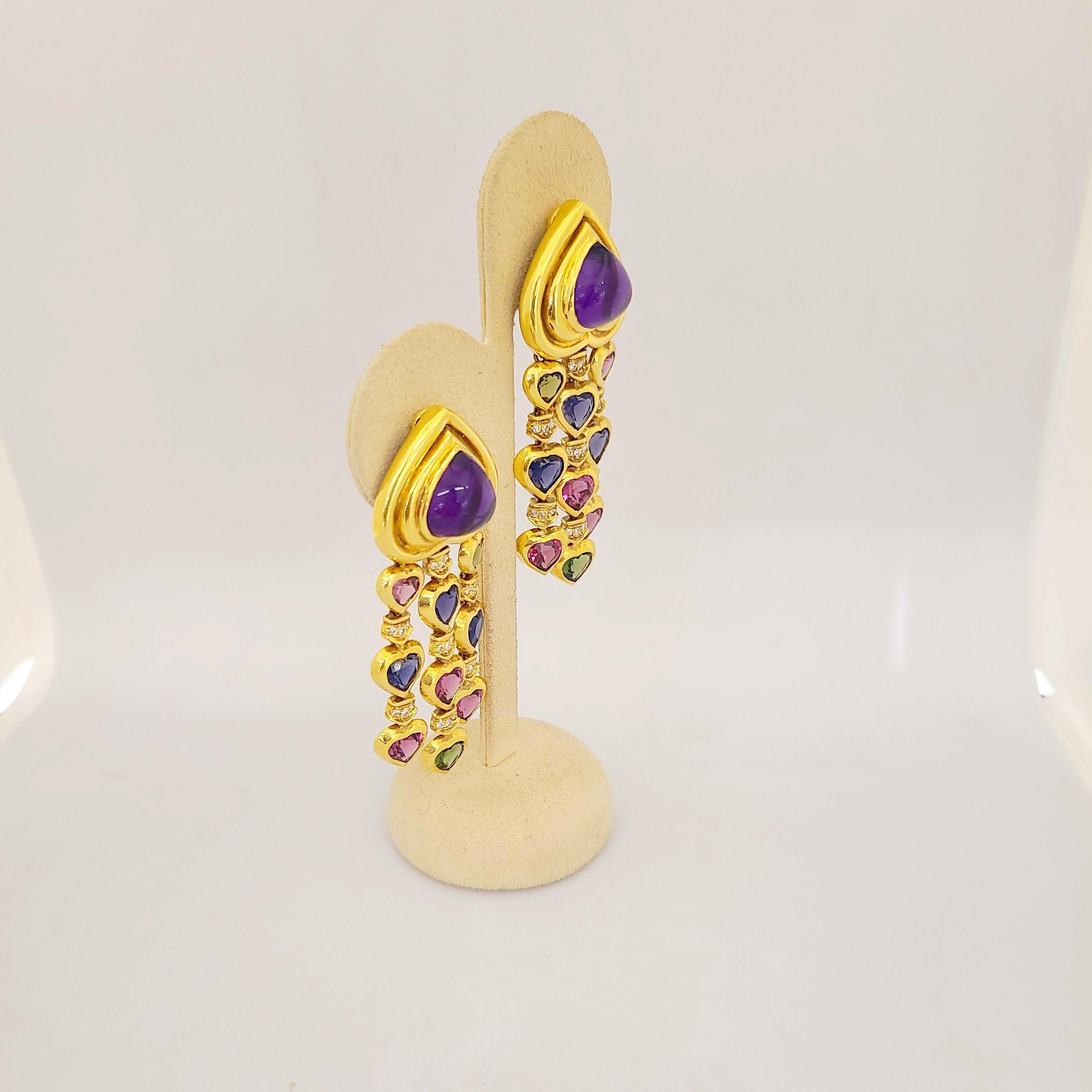 Set in 18 Karat Yellow Gold, These charming earrings are composed of two bezel set cabochon heart amethysts which have three rows of cascading small and mini multi colored bezel set semi-precious hearts. The semi precious stones are peridot, pink