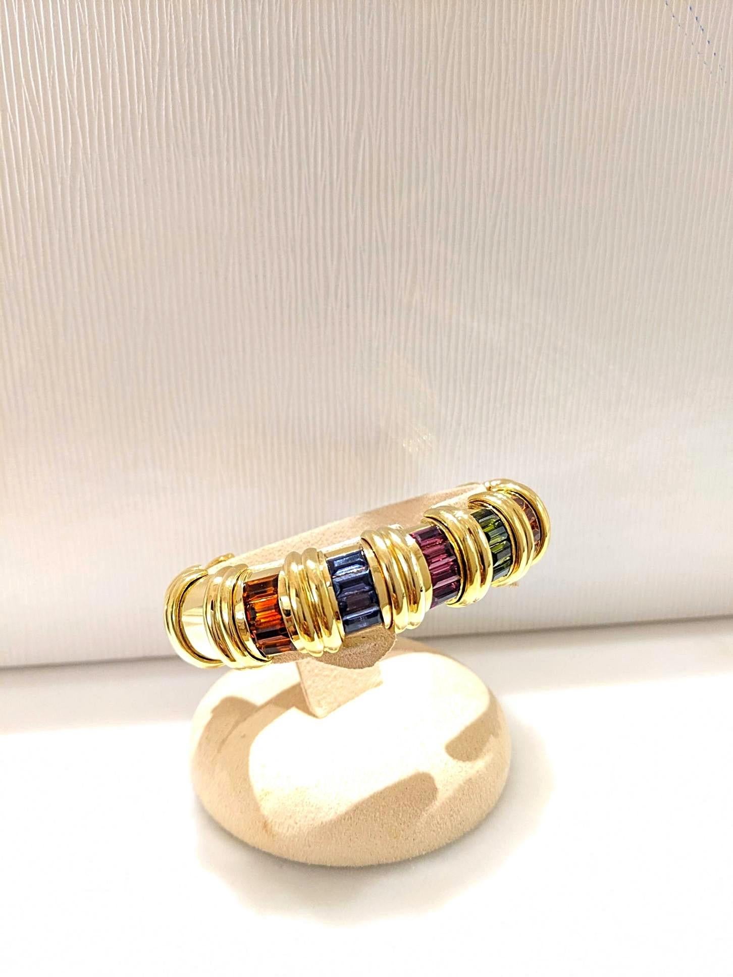 Cet élégant bracelet bangle de la collection arc-en-ciel du designer Jeffrey Stevens est réalisé en or jaune 18 carats. Cet élégant bracelet bangle est composé de 6 sections de pierres semi-précieuses de taille baguette invisiblement serties, dont