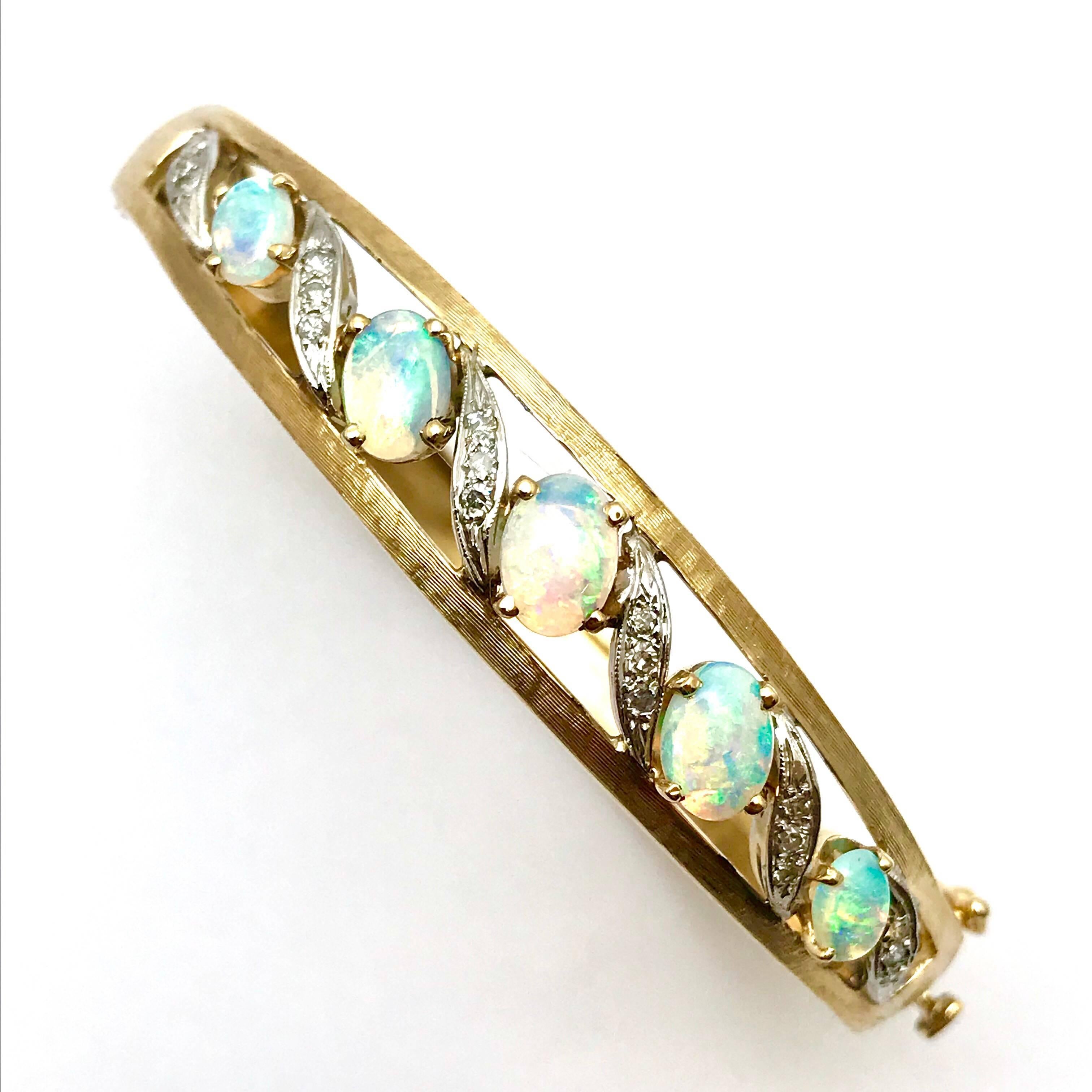A beautiful oval Jelly Opal and Single Cut Diamond 14 karat white and yellow gold bangle bracelet.  The top of the bracelet is designed with the Diamonds set in white gold in groups of three, alternating with the Opals.  The bangle has a satin