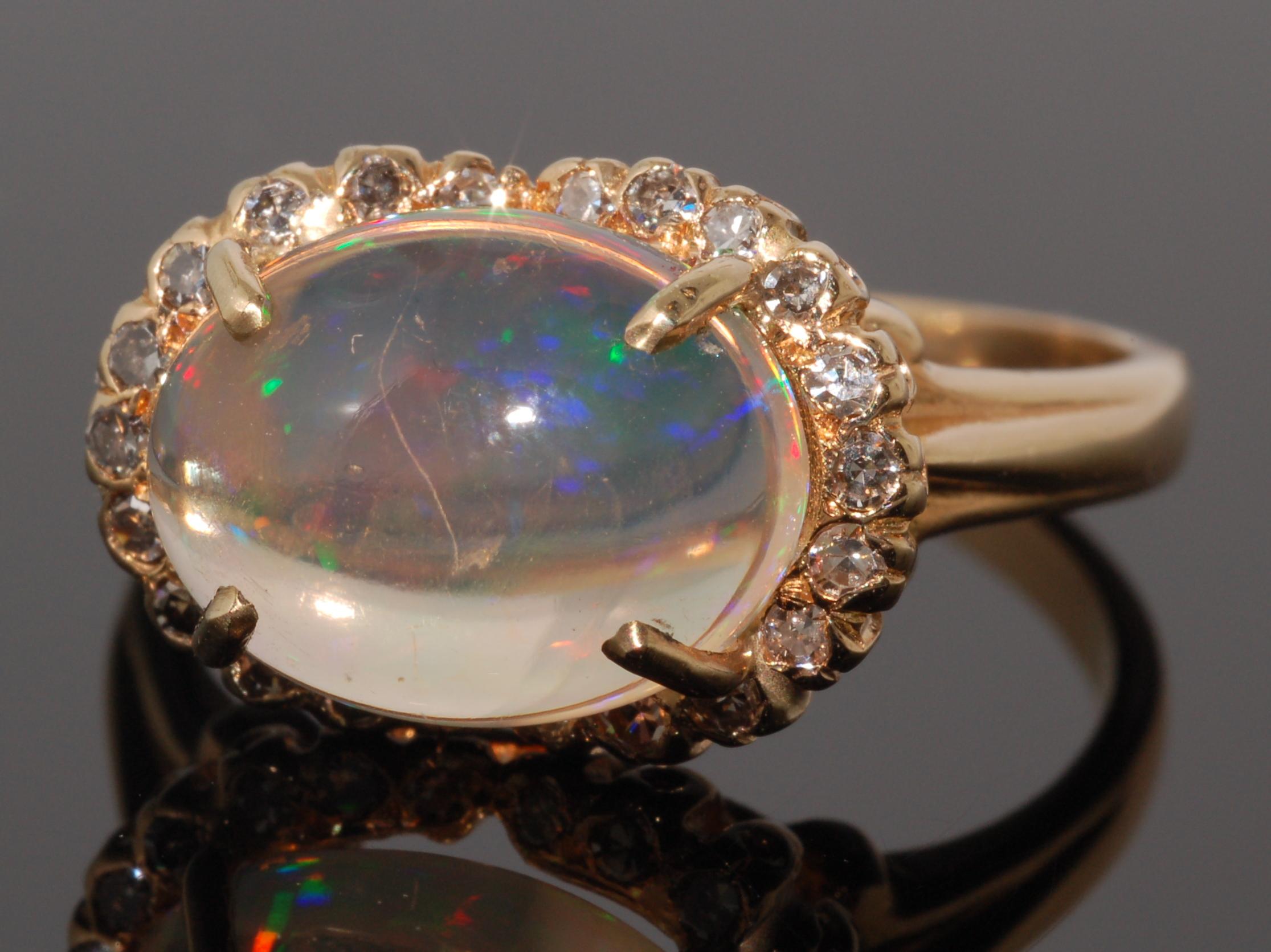 Jelly Opal and Diamond Cluster Ring

A transparent opal cabochon with red, green and yellow play of color, weighing approximately 3.90cts, is set within a scalloped halo of round diamonds totaling approximately 0.50ct, mounted in 18 karat yellow