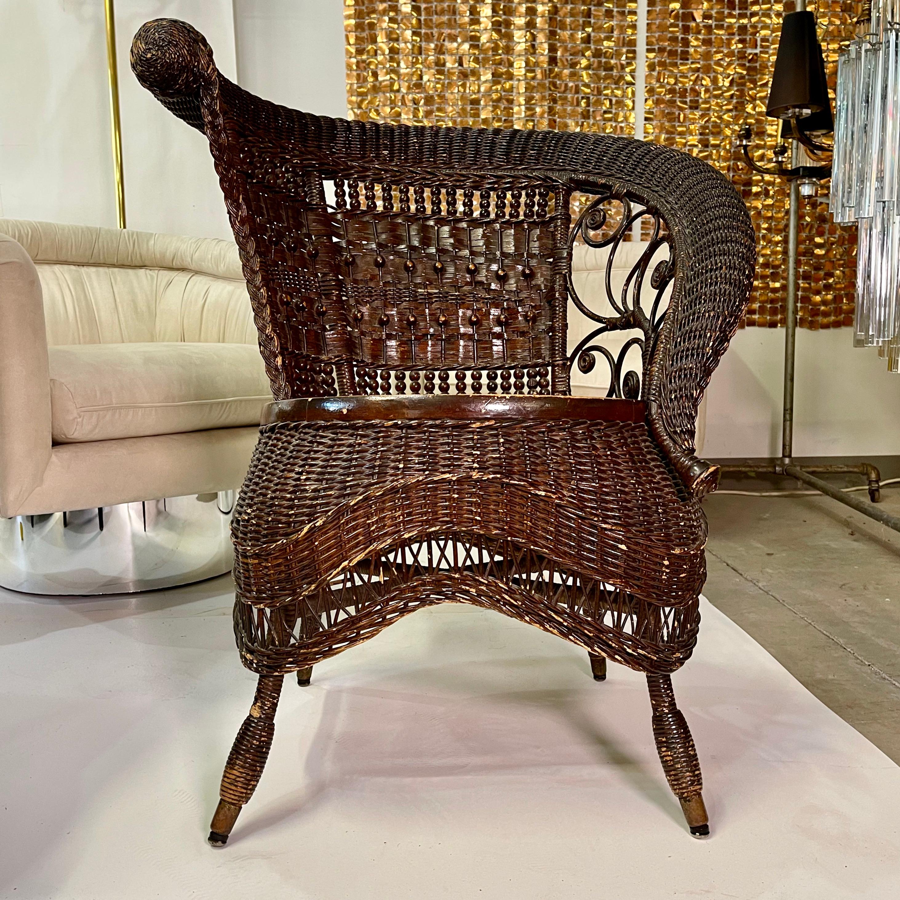 Jenkins & Phipps stick and ball wicker photographers or portrait chair with asymmetrical scrolled right arm and fiddleheads, woven skirt, and woven beaded front legs. 
Jenkins-Phipps label on underside, dating this chair from between 1903 and