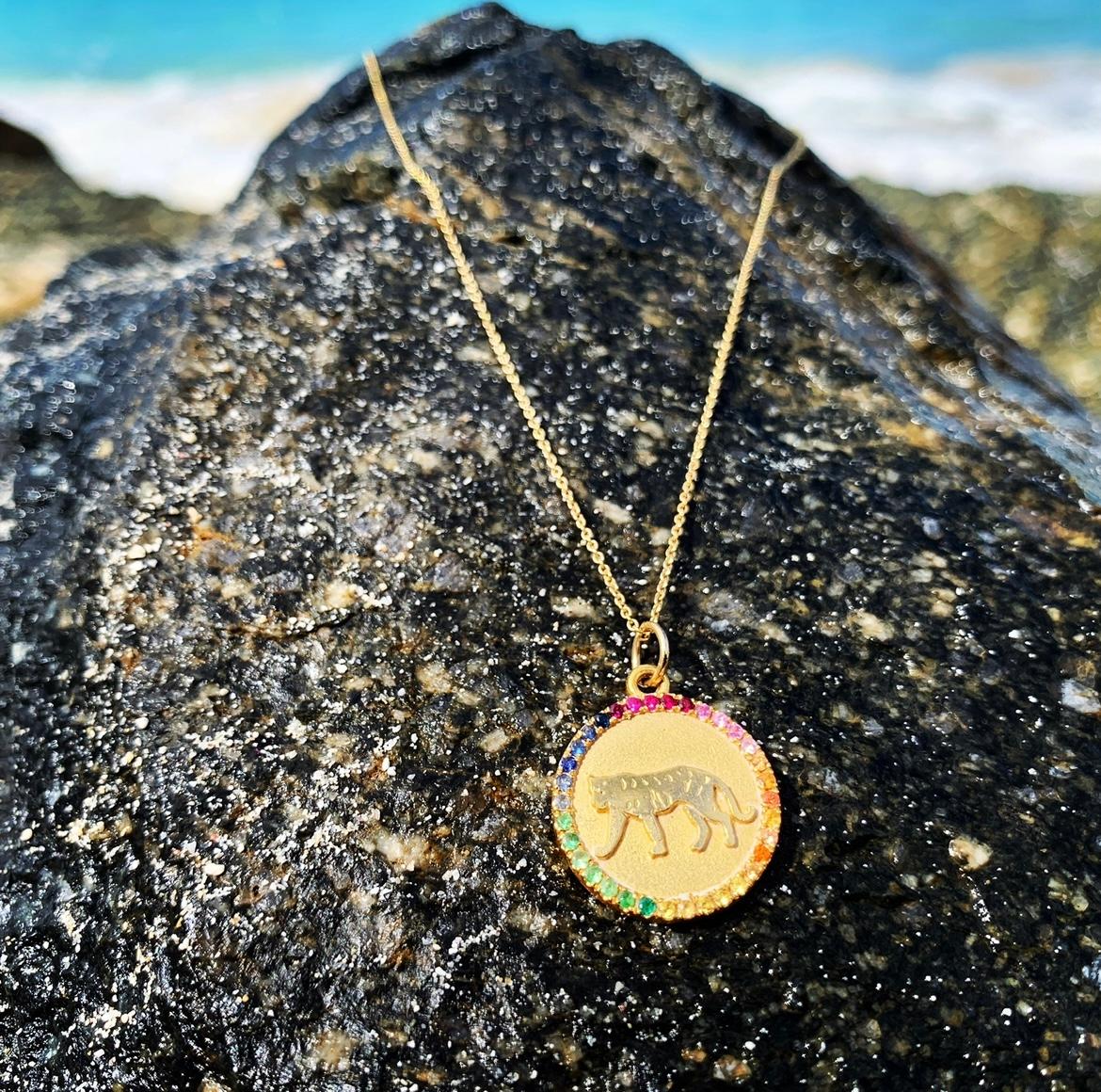 Unser Tiger-Medaillon wurde von Hand in Wachs geschnitzt und in 14 kt Gold gegossen,  und mit Edelsteinen aus Regenbogensaphiren verziert.  Unser Tiger repräsentiert eines der zwölf Tierzeichen des chinesischen Zodiacs.  Jedes Medaillon ist 18 mm
