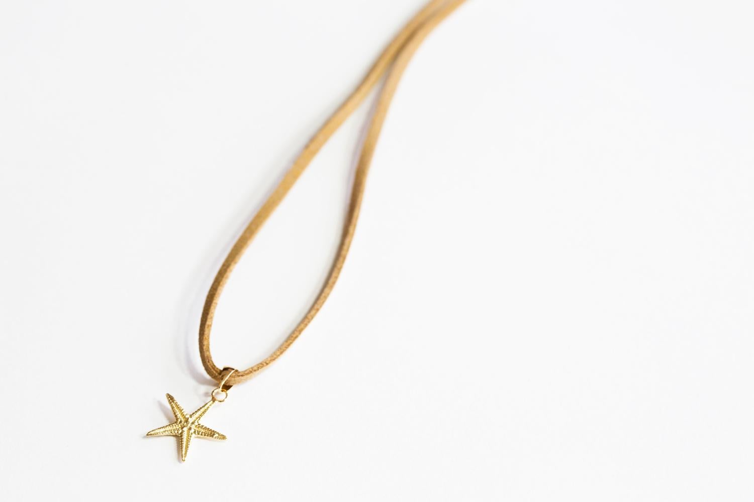 Piccolo charm a forma di stella marina fuso dalla natura in oro 14kt. Diametro dello charme 10 mm. Catena in oro 14kt da 18 pollici inclusa.