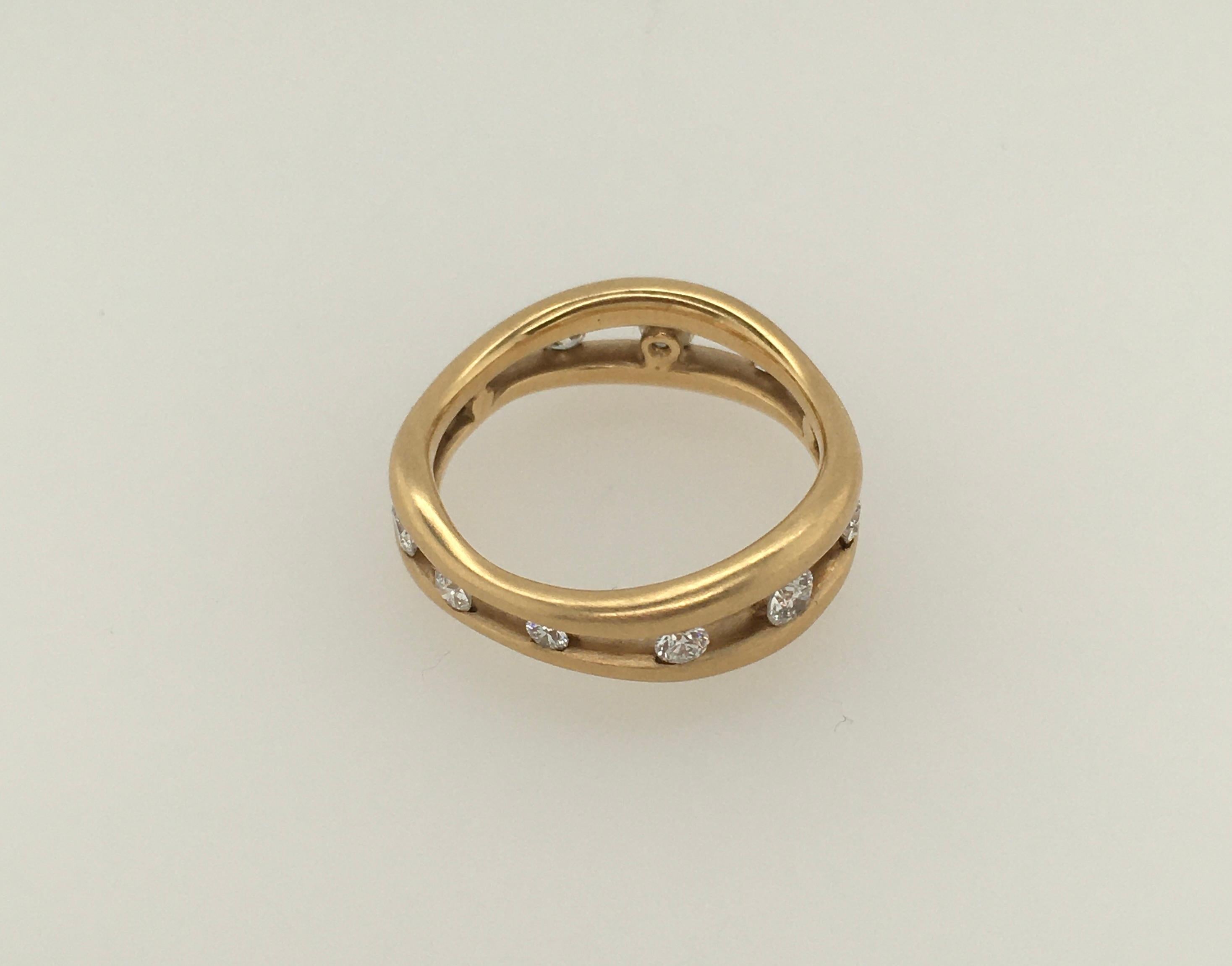 This delicate Jennifer Shigetomi creation features two 14k gold wedding bands joined together to hold 12 floating .57 TCW micro bead diamonds that encircle the ring. The finish is a lovely combination of satin and polished gold.  At its widest point