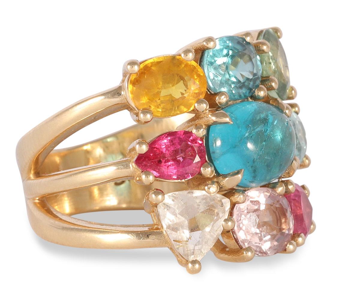 One oval Paraiba colored apatite cabochon is surrounded by multi colored sapphires and tourmalines. The prong settings on this three row gem candy ring show off the beauty and sparkle of this statement ring that pops with color, adding endless joy