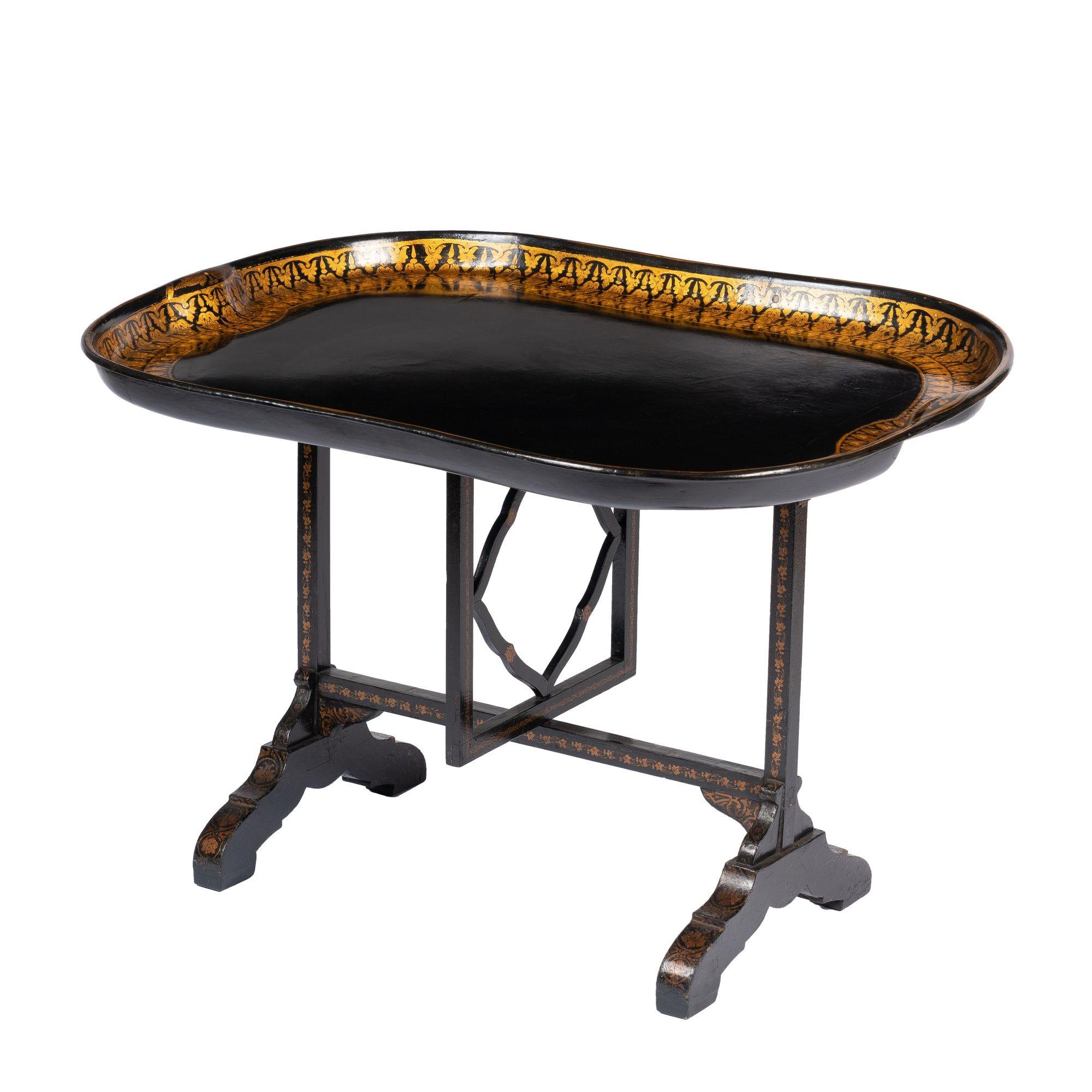 Shaped paper mache tray mounted on a butterfly hinged tilt top support, based on the French Vendange table mechanism. The black tray has a double border decoration of a gilt anthemion on a yellow ground, and the tray is mounted on its original