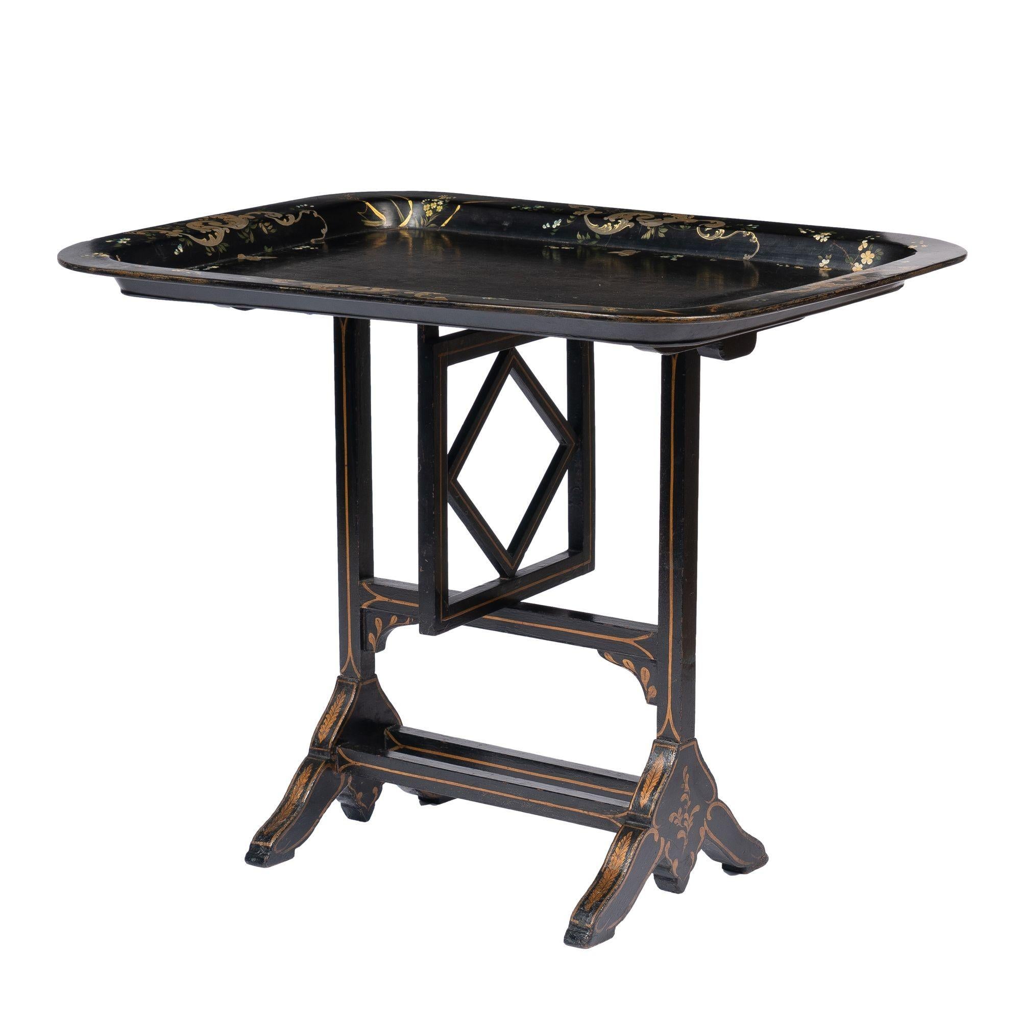 Table plateau à thé rectangulaire en papier mâché avec un bord plat et des coins arrondis. Le plateau est orné d'une décoration de volutes et de bordures florales peintes à la main et est monté sur un support pivotant en bois ébénisé Jennings &