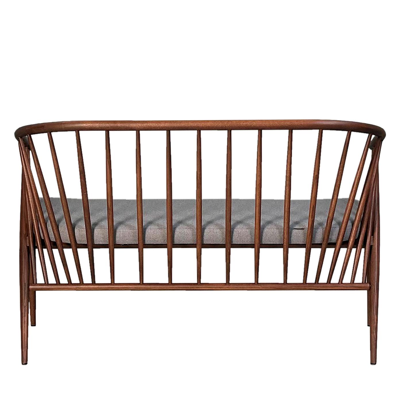 Jenny ist ein exquisites, mit handwerklicher Präzision gefertigtes Holzsofa, das zeitlose Eleganz ausstrahlt. Das Gestell aus Eschenholz, sorgfältig gedrechselt und geformt, weist ein einzigartiges Design auf, bei dem sich die Rückenlehne anmutig an