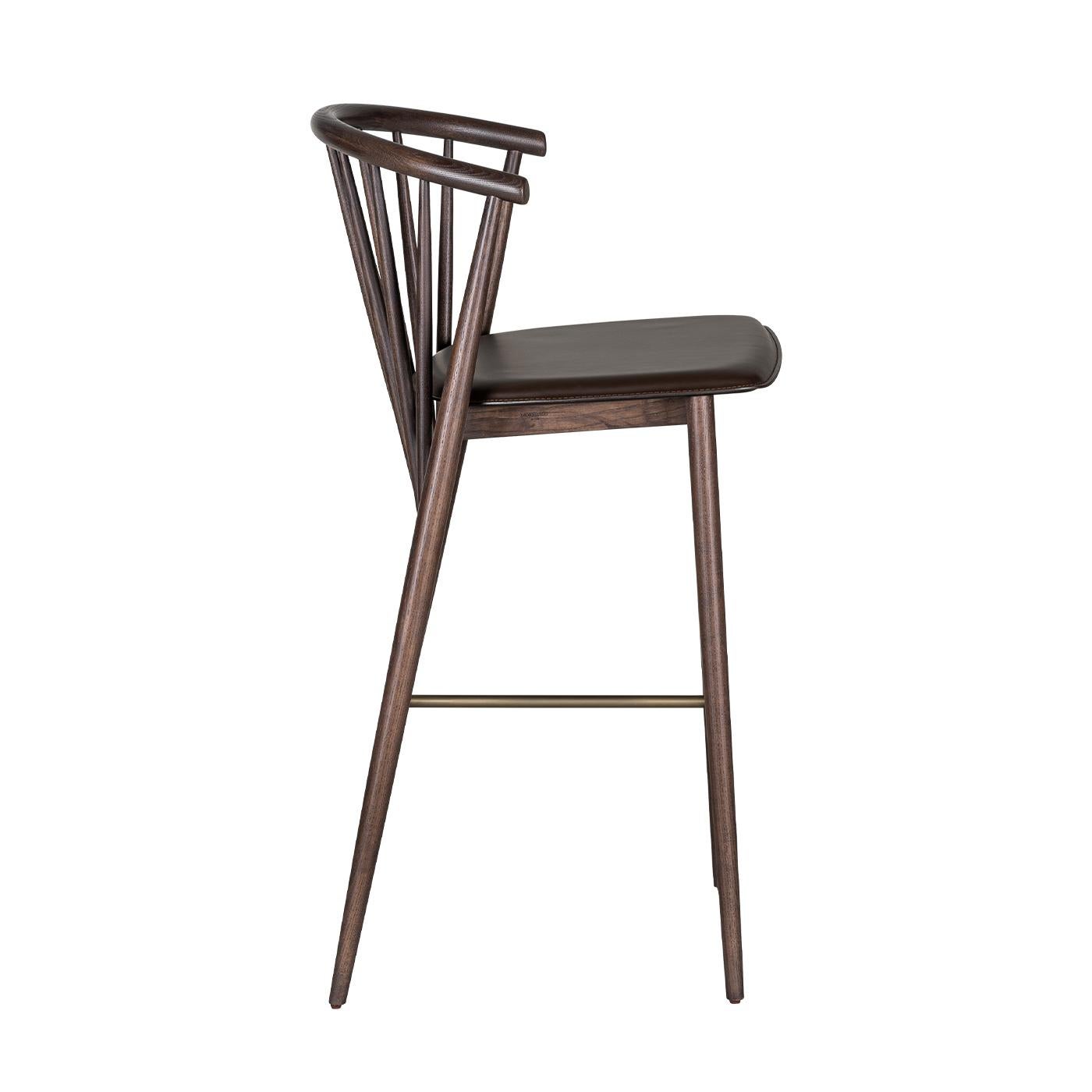 A distinctive bar stool with a charming retro allure. Entirely crafted in elegant brown ash wood and showcasing an iconic Americana rounded spindle back. Enhanced by a sleek metal footrest and matching upholstered seat. 