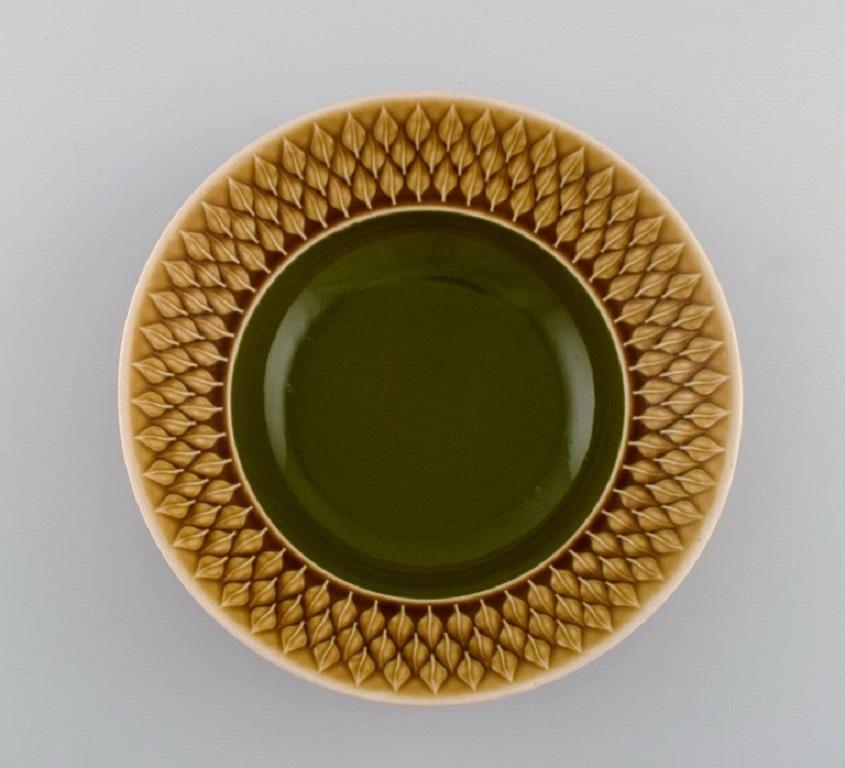 Jens H. Quistgaard (1919-2008) for Bing & Grøndahl. 
Twelve Relief deep plates in glazed stoneware. Beautiful glaze in mustard yellow and green shades. 1960s.
Measures: 21.5 x 6 cm.
In excellent condition.
Stamped.