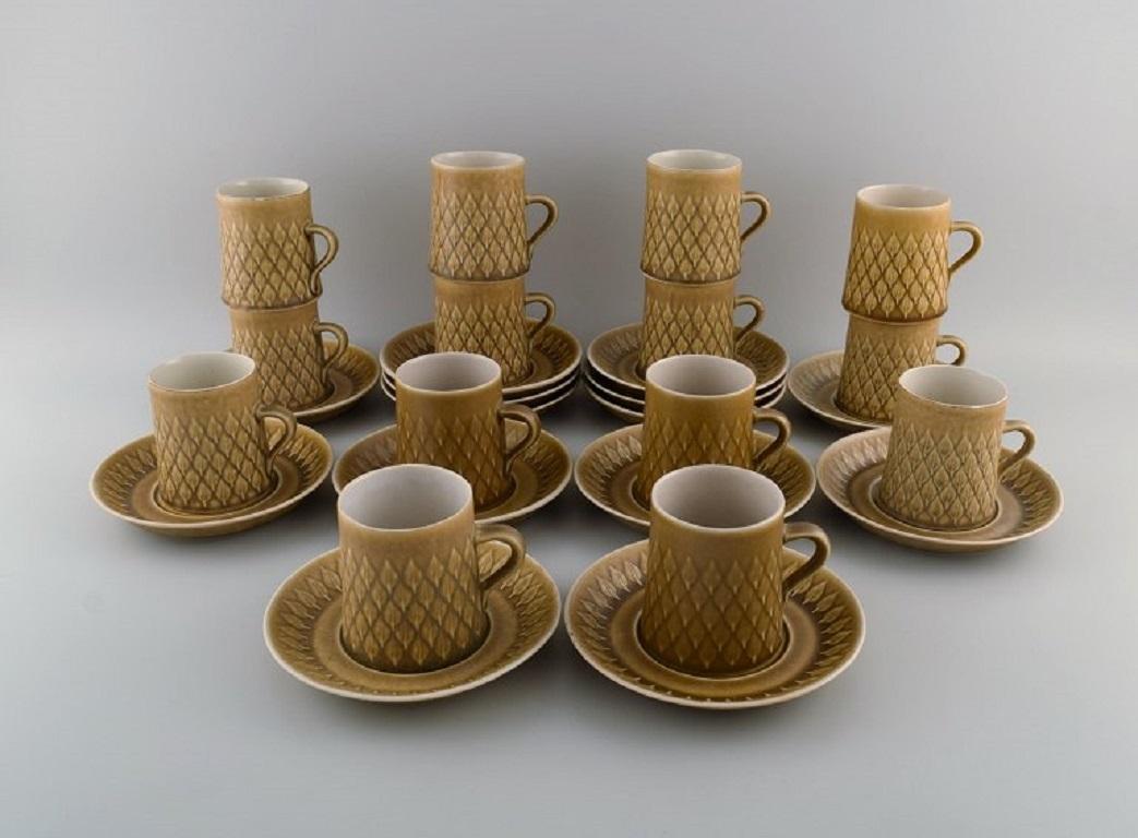 Jens H. Quistgaard (1919-2008) for Bing & Grøndahl / Nissen Kronjyden. 
14 Relief coffee cups with saucers in glazed stoneware. Beautiful glaze in mustard yellow shades. 1960s.
The cup measures: 8 x 6.5 cm.
Saucer diameter: 15 cm.
In excellent