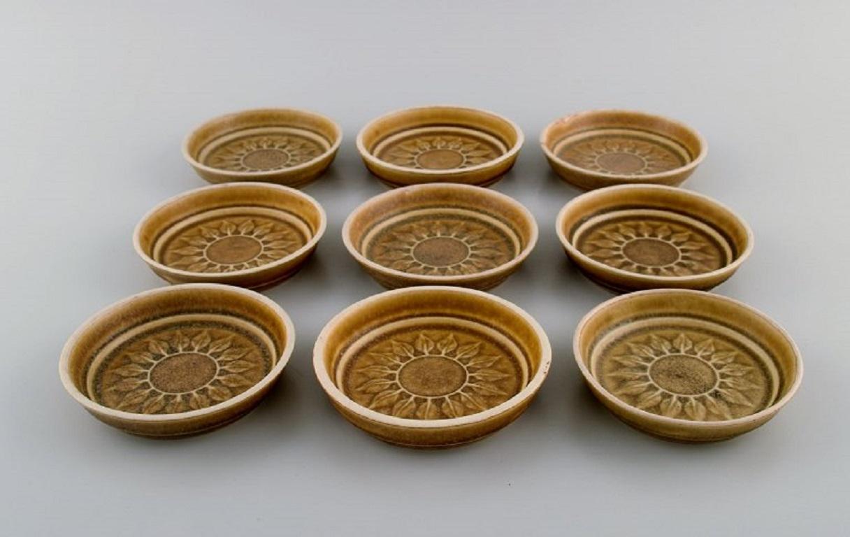 Jens H. Quistgaard (1919-2008) for Bing & Grøndahl / Nissen Kronjyden. 
9 Relief bowls / bottle trays in glazed stoneware. Beautiful glaze in mustard yellow shades. 1960s.
Measures: 10.5 x 2 cm.
In excellent condition.
Stamped.