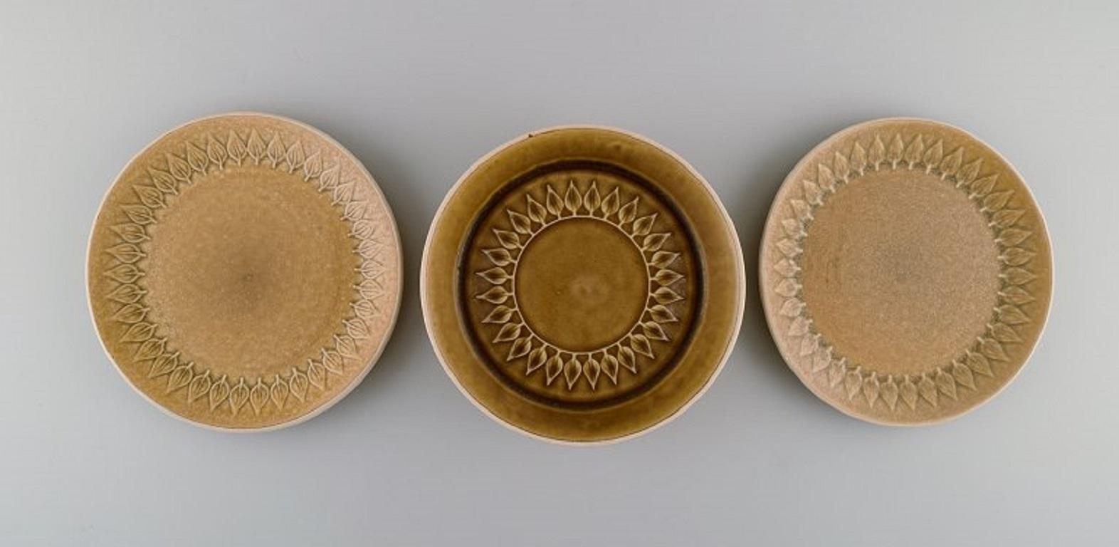 Jens H. Quistgaard (1919-2008) for Bing & Grøndahl / Nissen Kronjyden. 
Relief bowl and two plates in glazed stoneware. Beautiful glaze in mustard yellow shades. 1960s.
The bowl measures: 18.5 x 6 cm.
Plate diameter: 19.5 cm.
In excellent