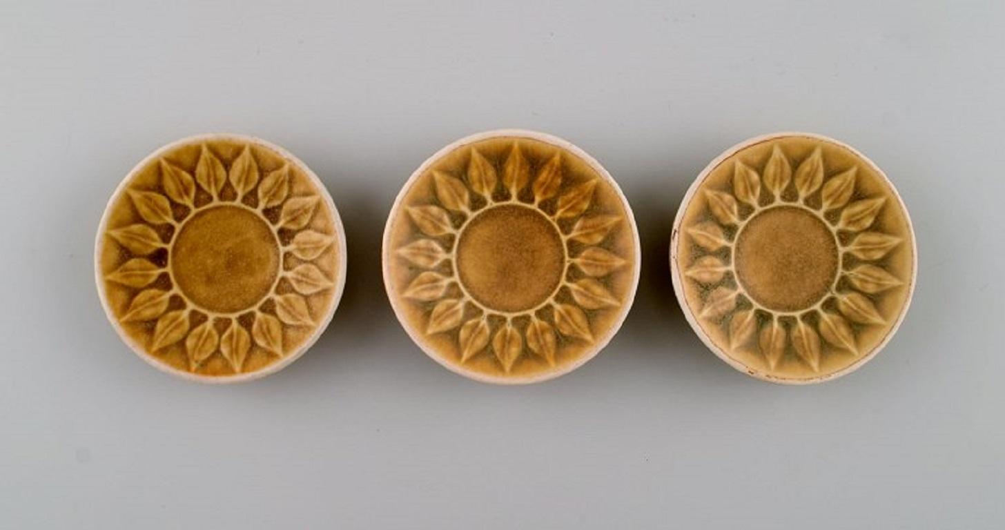Jens H. Quistgaard (1919-2008) for Bing & Grøndahl / Nissen Kronjyden. 
Seven parts Relief in glazed stoneware. Beautiful glaze in mustard yellow shades. 1960s.
The candlestick measures: 11 x 3.5 cm.
Largest cup / vase measures: 7.3 x 6.3 cm.
In